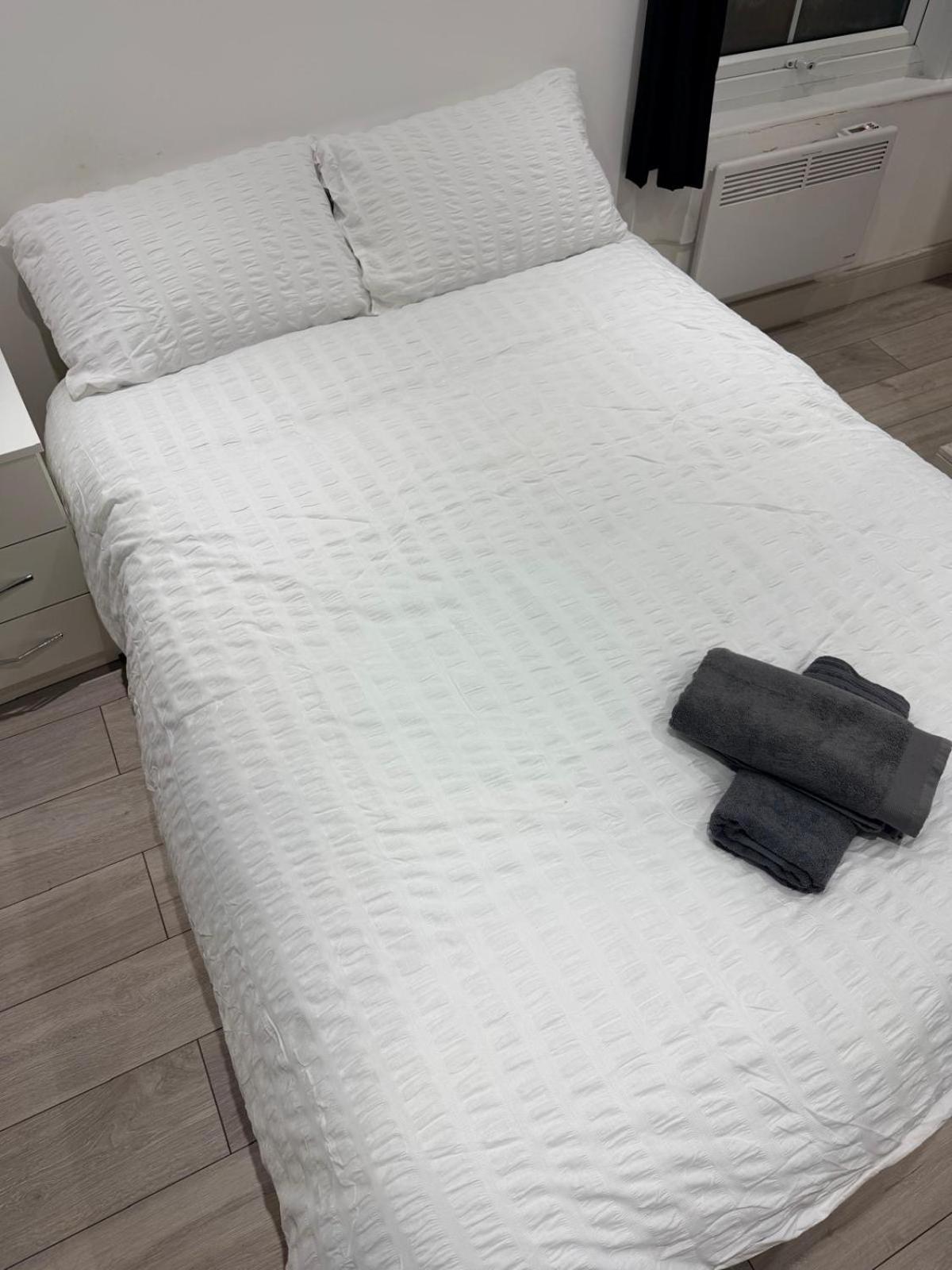 a white bed with two towels on top of it at Modern Studios Elephant and Castle in London