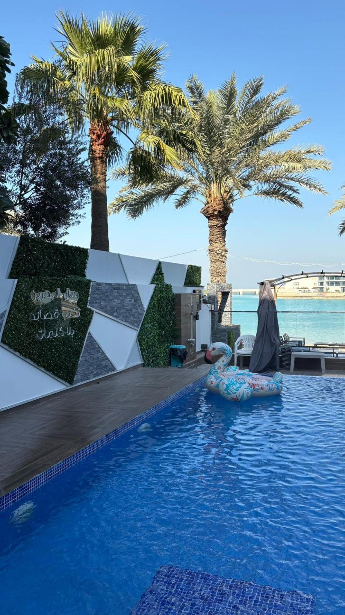 a woman sitting on an inflatable raft in a pool with palm trees at شالية Vipمرسى البحرين 4 غرف مسبح خاص وشاطى in Muharraq