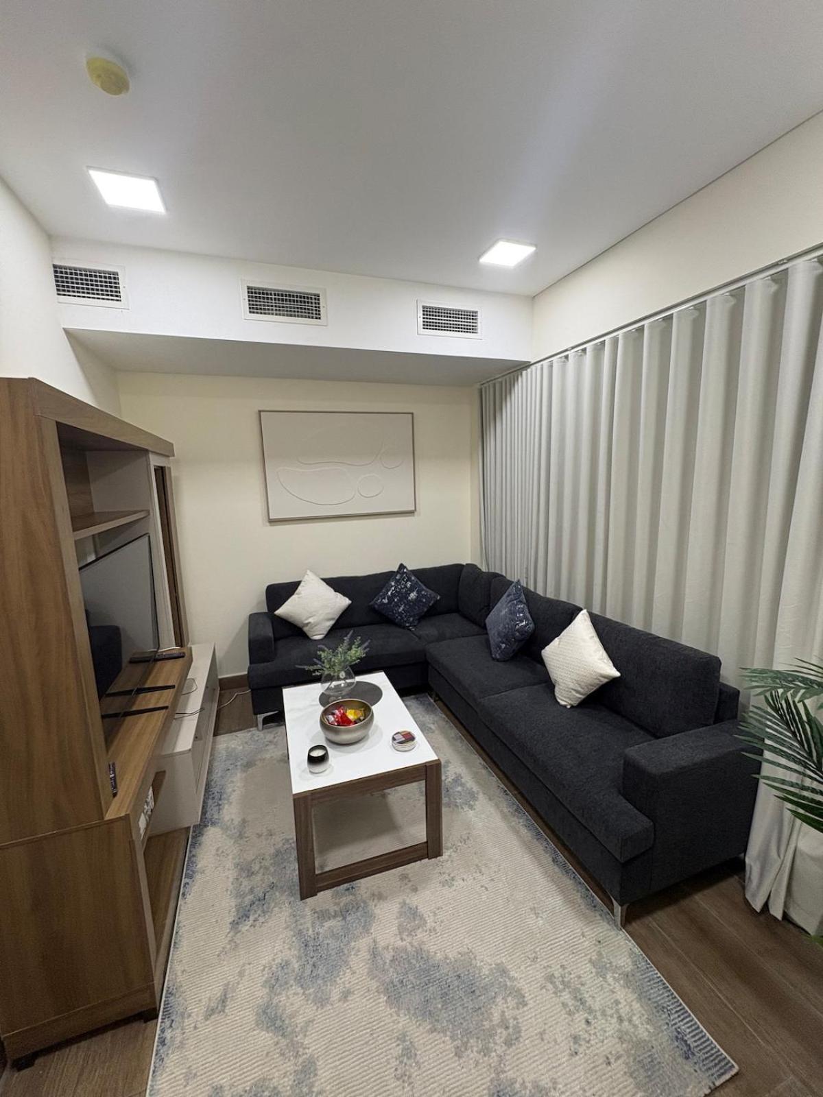 a living room with a black couch and a table at جناح الملكي غرفتين بمسبح خاص نظام التدفئة in Amwaj Island