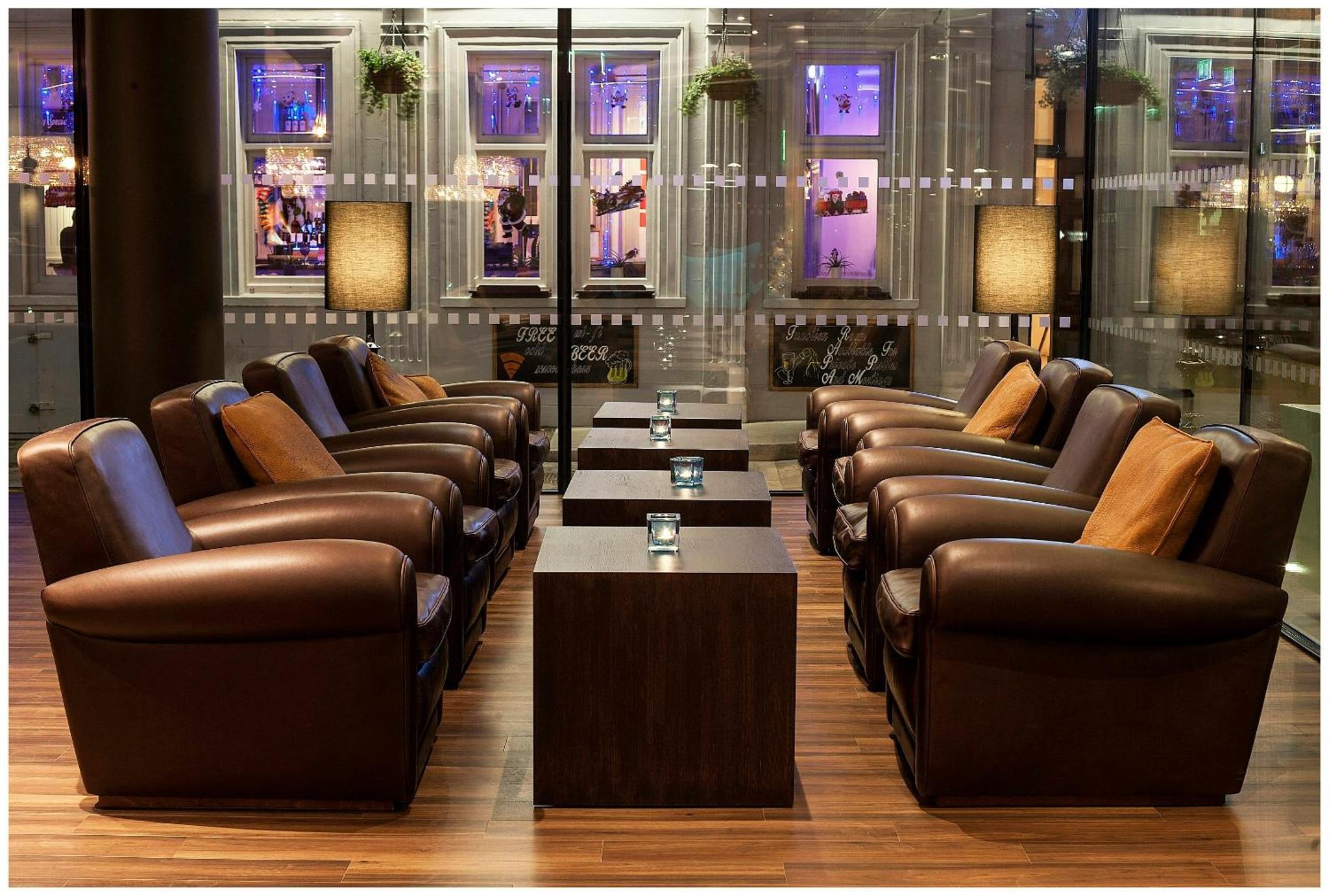 a bar with leather chairs and a table and windows at Motel One London-Tower Hill in London +18 photos