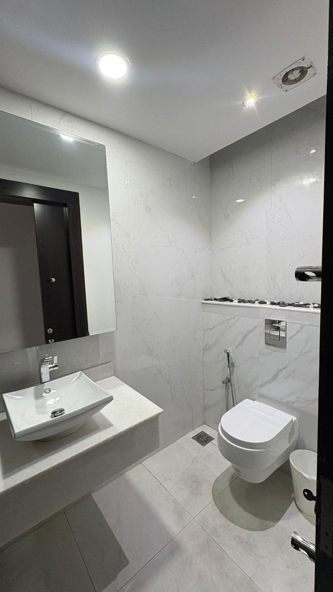 a white bathroom with a toilet and a sink at شقة فخمة بإطلالة بحرية في امواج in Muharraq