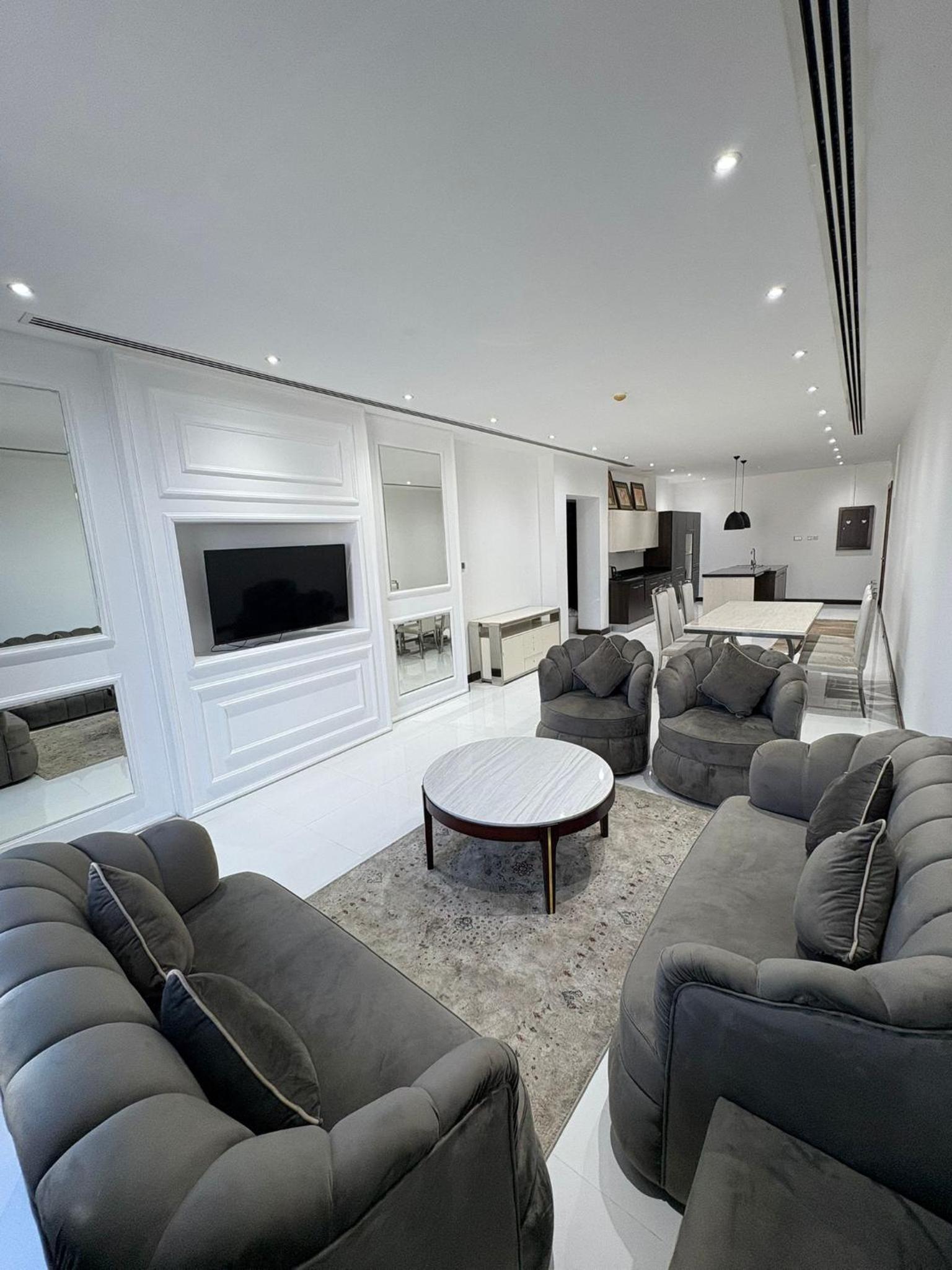 a living room with couches and a tv and a table at شقة فخمة بإطلالة بحرية في امواج in Muharraq