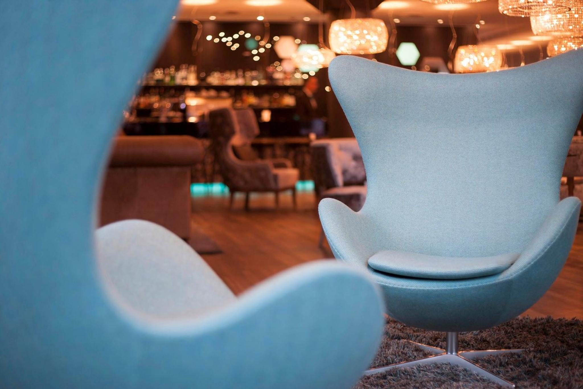 two white chairs in a room with a bar at Motel One London-Tower Hill in London