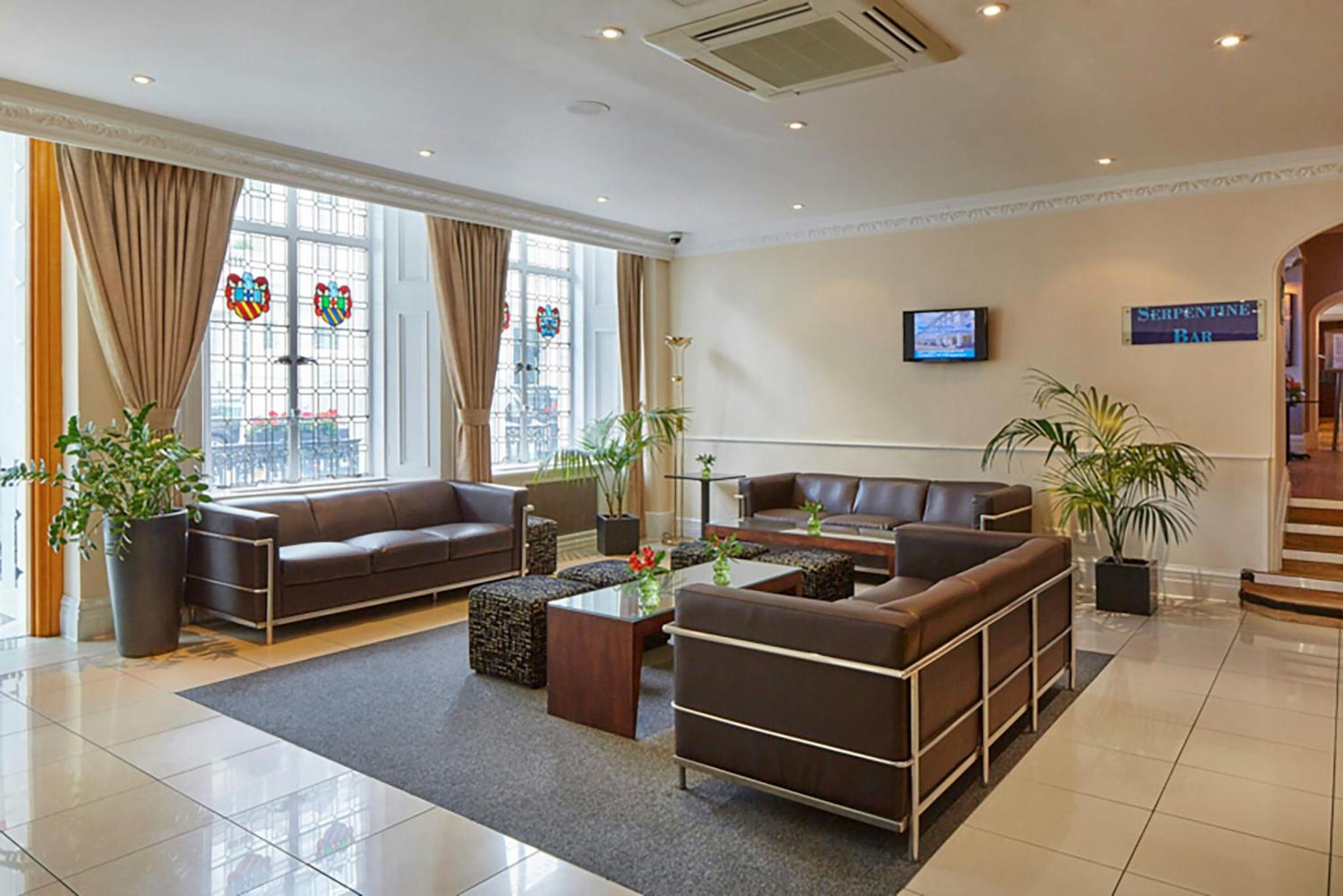 a living room with couches and a table at Lancaster Gate Hotel in London