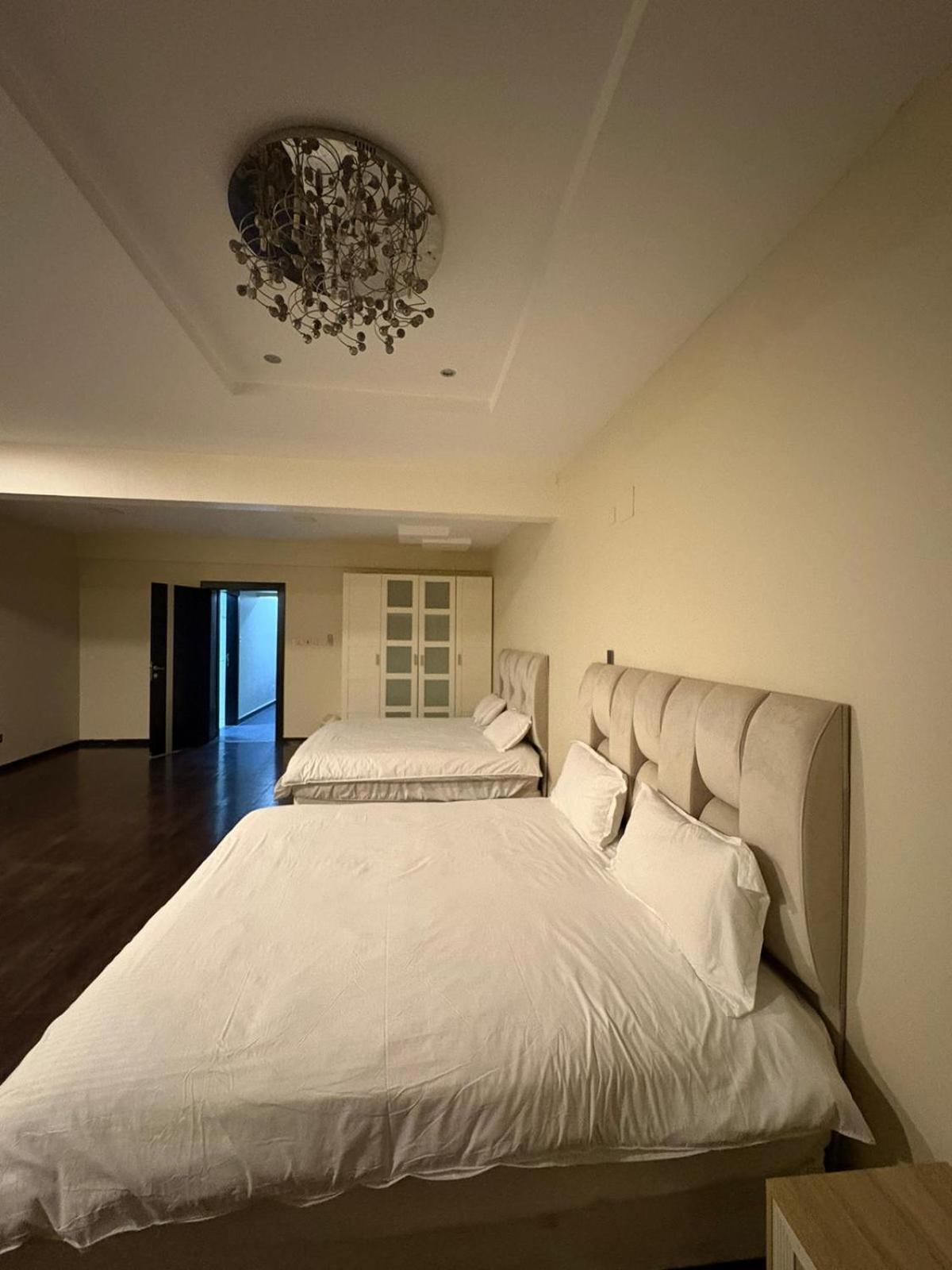 a large white bed in a bedroom with a chandelier at شاليةسرايا البحر4 غرف نوم مسبح خاص وبحر in Amwaj Island