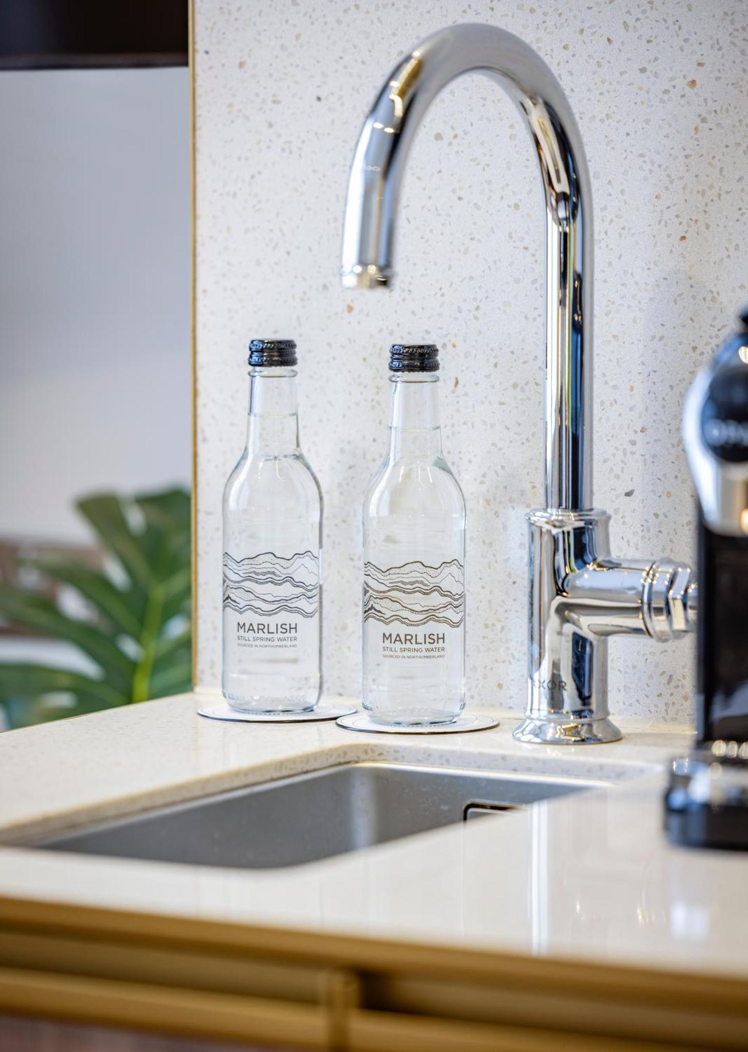 two bottles of water sitting next to a kitchen sink at Dao by Dorsett North London in London