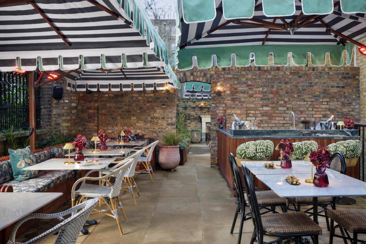 a restaurant with tables and chairs and a brick wall at Bertrand's Townhouse in London