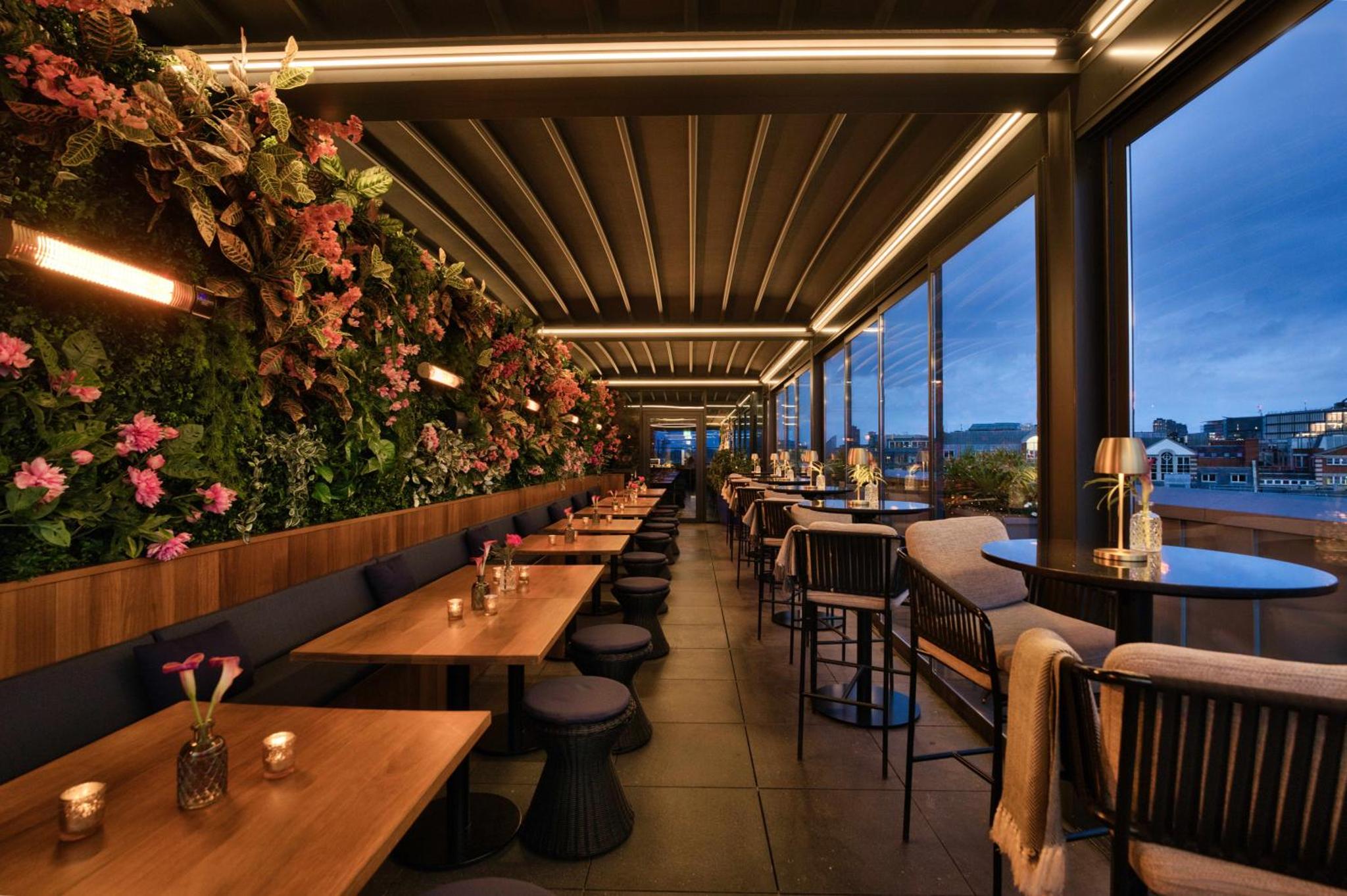 a row of tables in a restaurant with flowers at Hotel AMANO Covent Garden in London