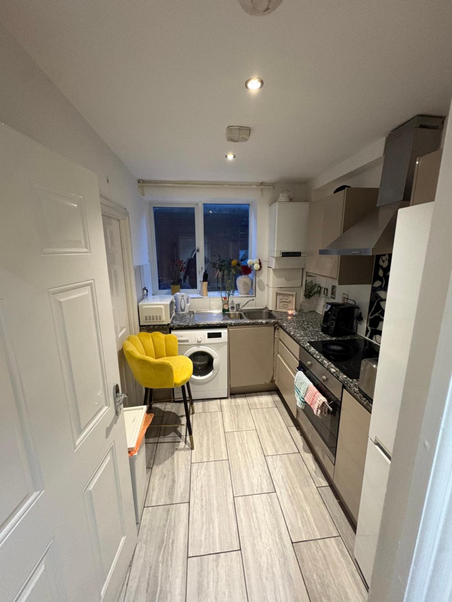 a kitchen with a yellow chair in the middle at Tower Bridge Luxury Apartment with Balcony in London