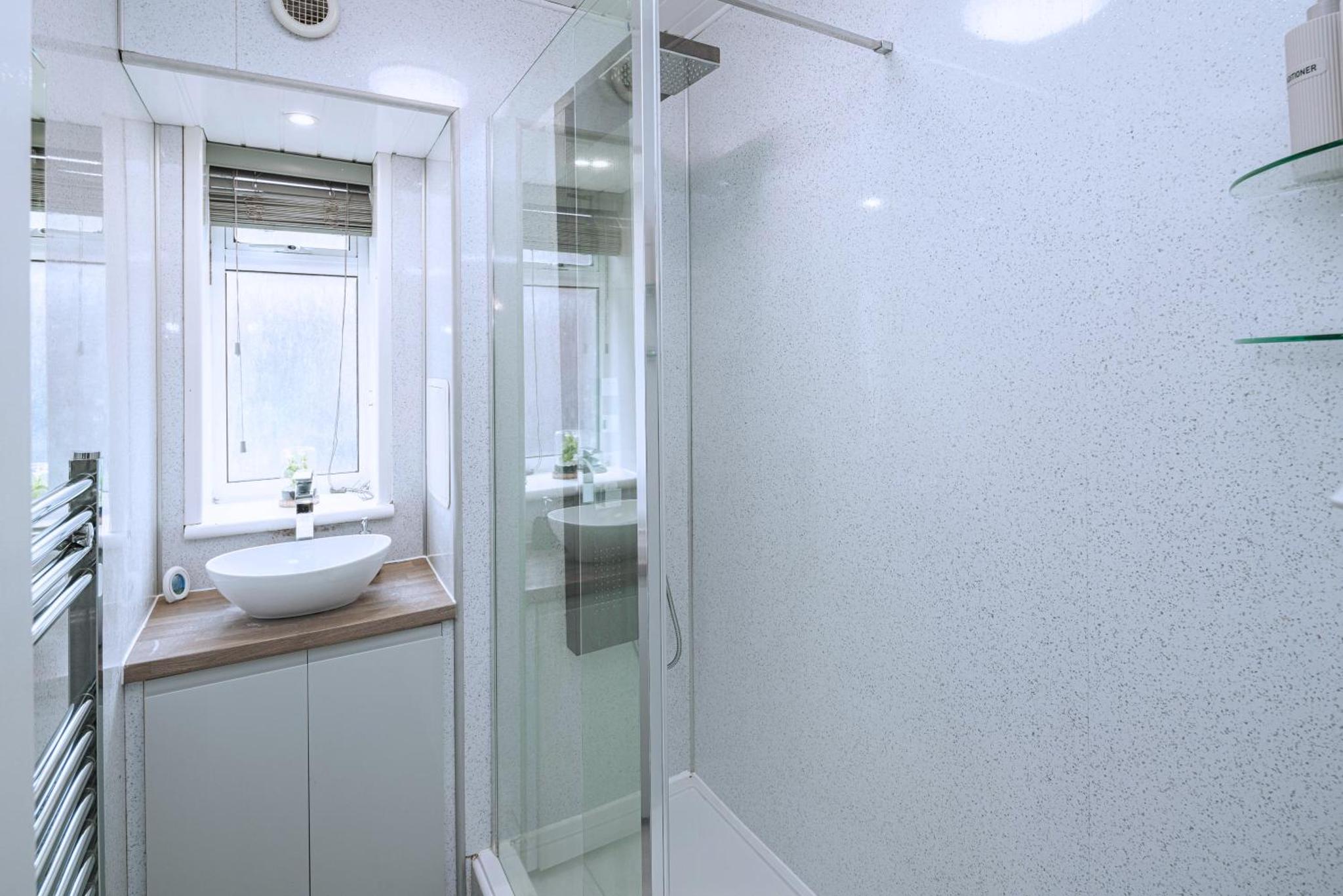a bathroom with a glass shower and a sink at Modern 3BR with Fast Links to Central London in London