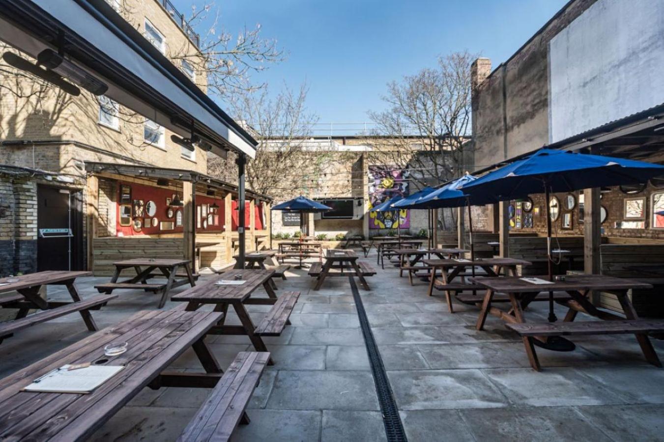 a row of wooden tables and umbrellas on a patio at The Red Lion Hotel in London