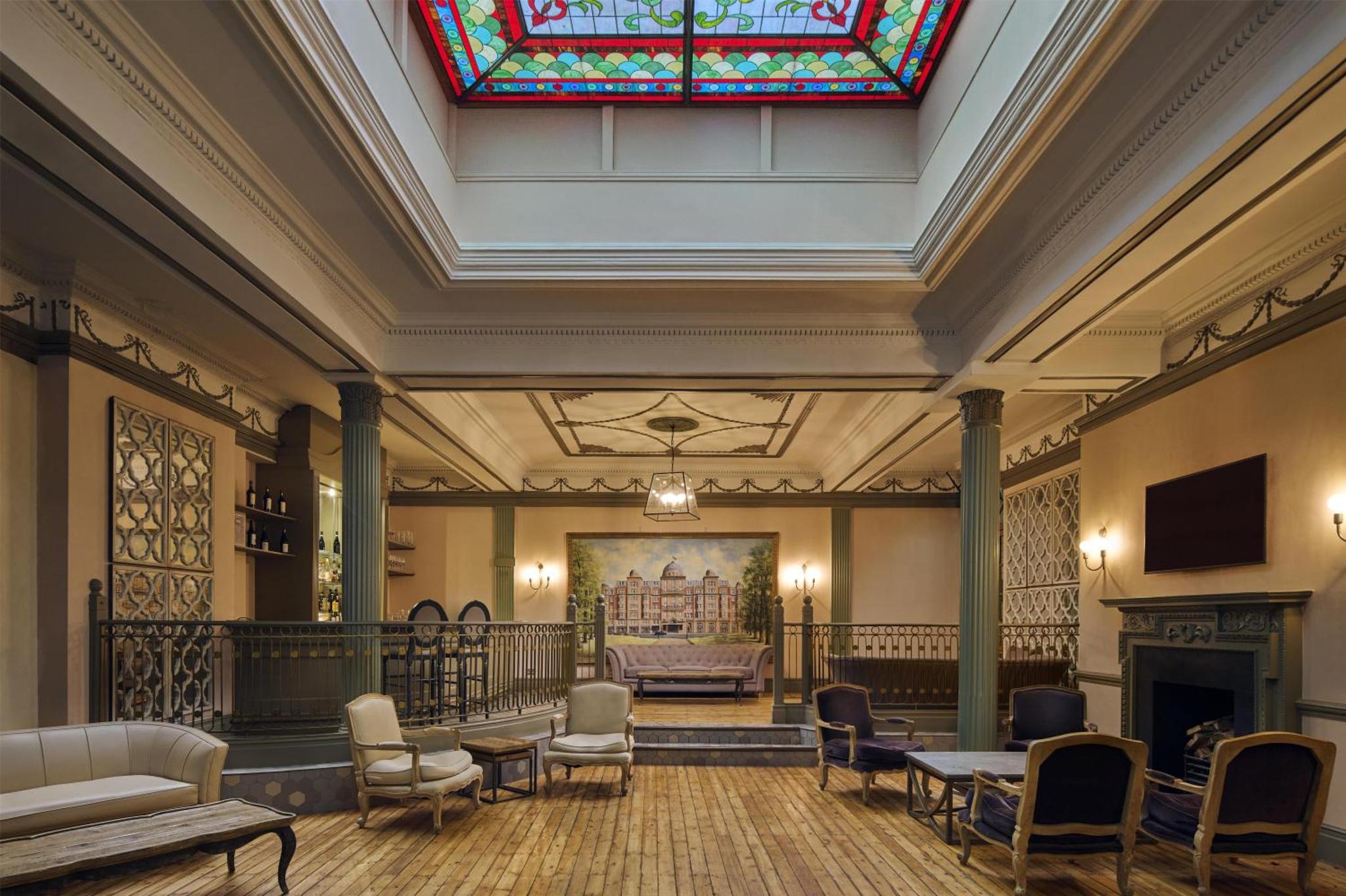 a lobby with a stained glass window and a fireplace at Hilton London Hyde Park in London