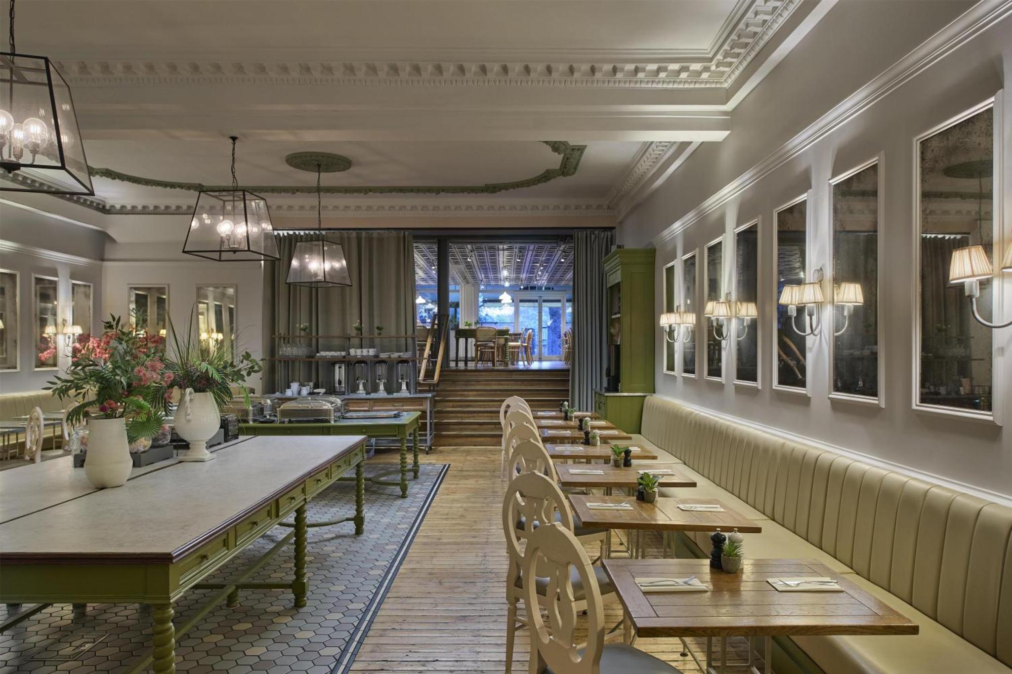 a restaurant with wooden tables and chairs and a hallway at Hilton London Hyde Park in London