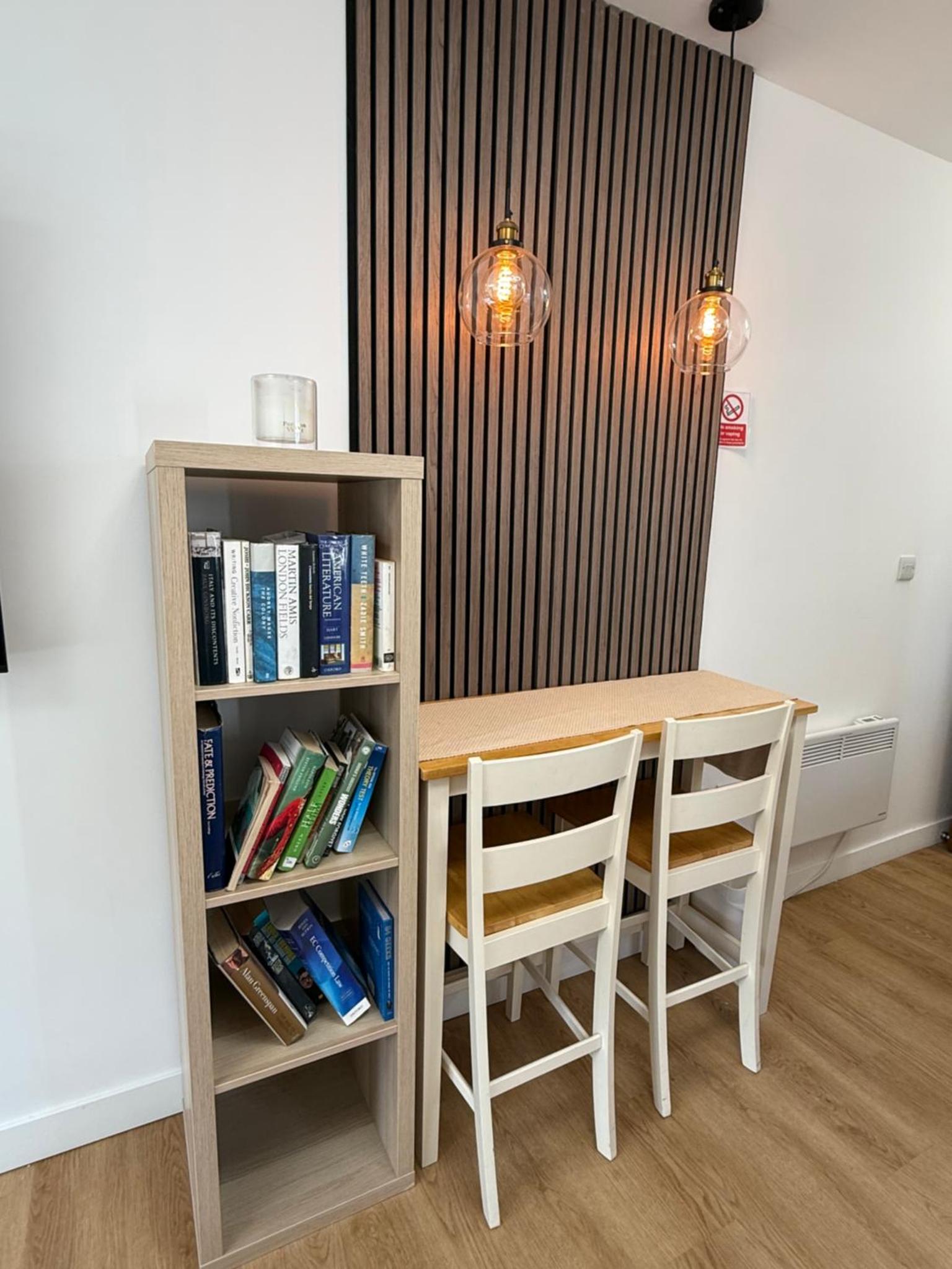 a table with two chairs and a book shelf with books at Modern East London Apartment with Private Studio & Guest Rooms-Near Bow, Victoria Park in London +67 photos