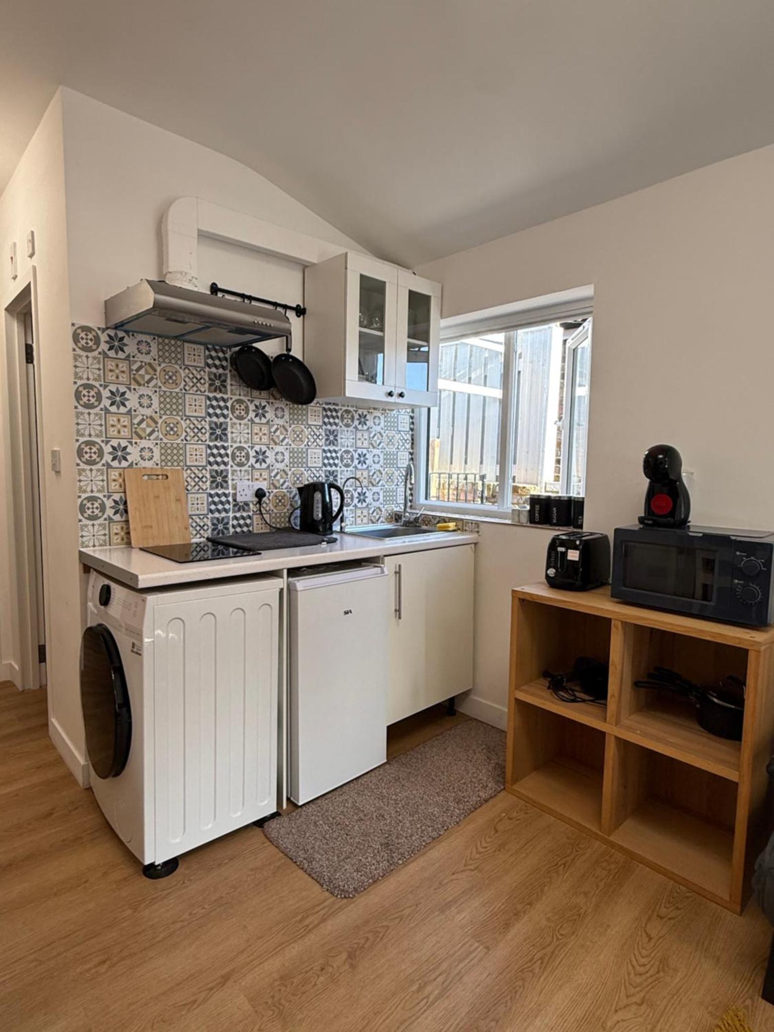 a kitchen with white cabinets and a stove top oven at Modern East London Apartment with Private Studio & Guest Rooms-Near Bow, Victoria Park in London