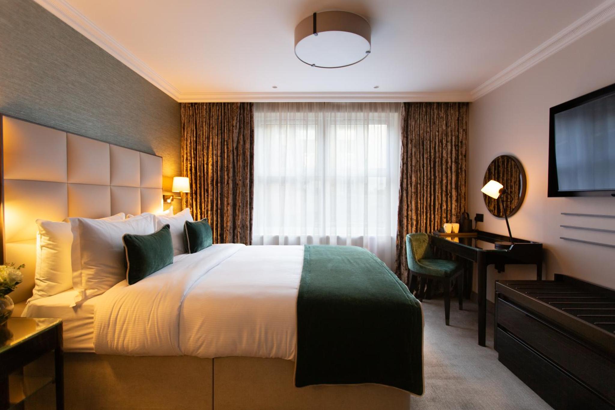 a hotel room with a bed and a desk and a television at The Rathbone Hotel, Fitzrovia in London