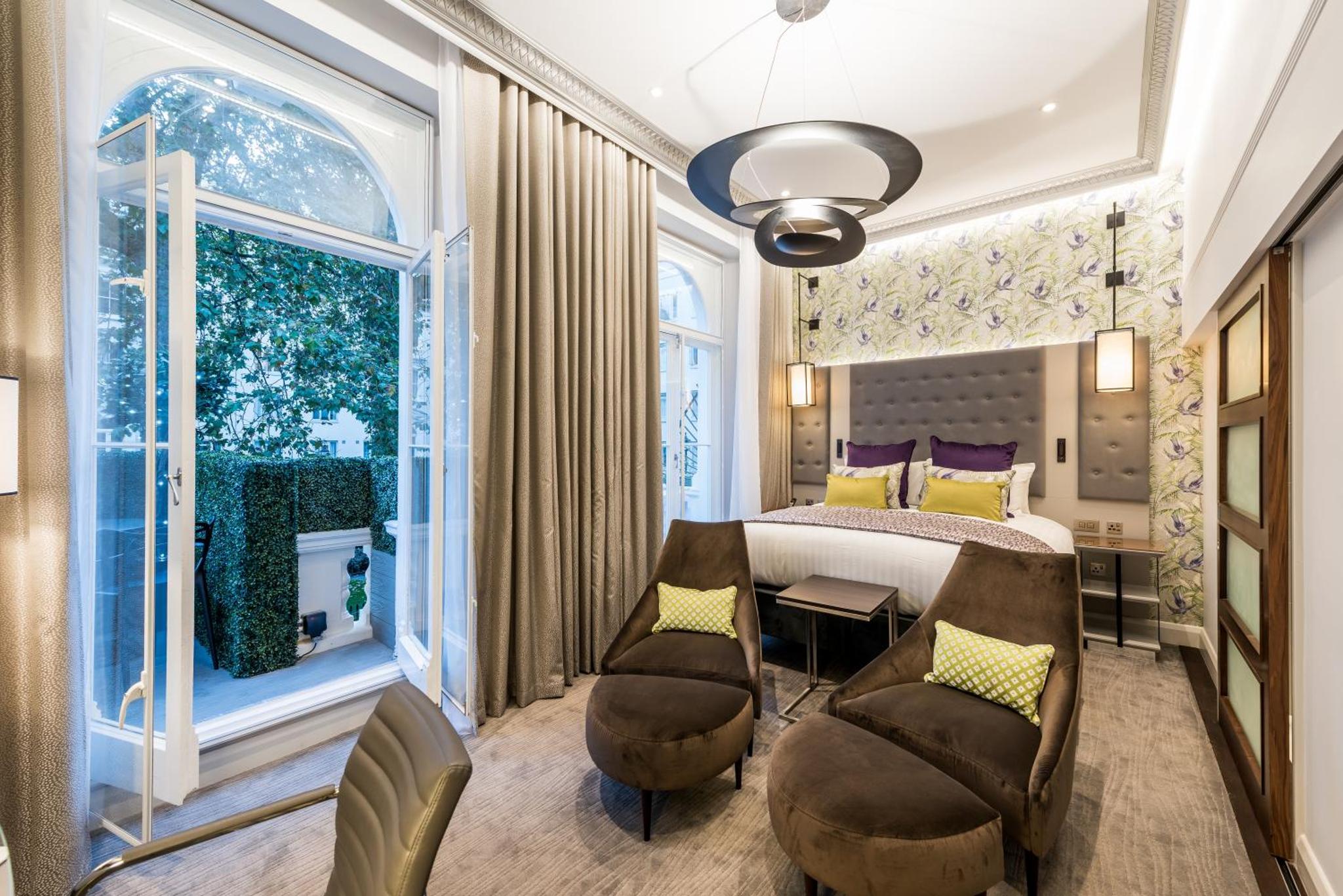 a bedroom with a bed and a table and chairs at Mercure London Hyde Park Hotel in London +97 photos