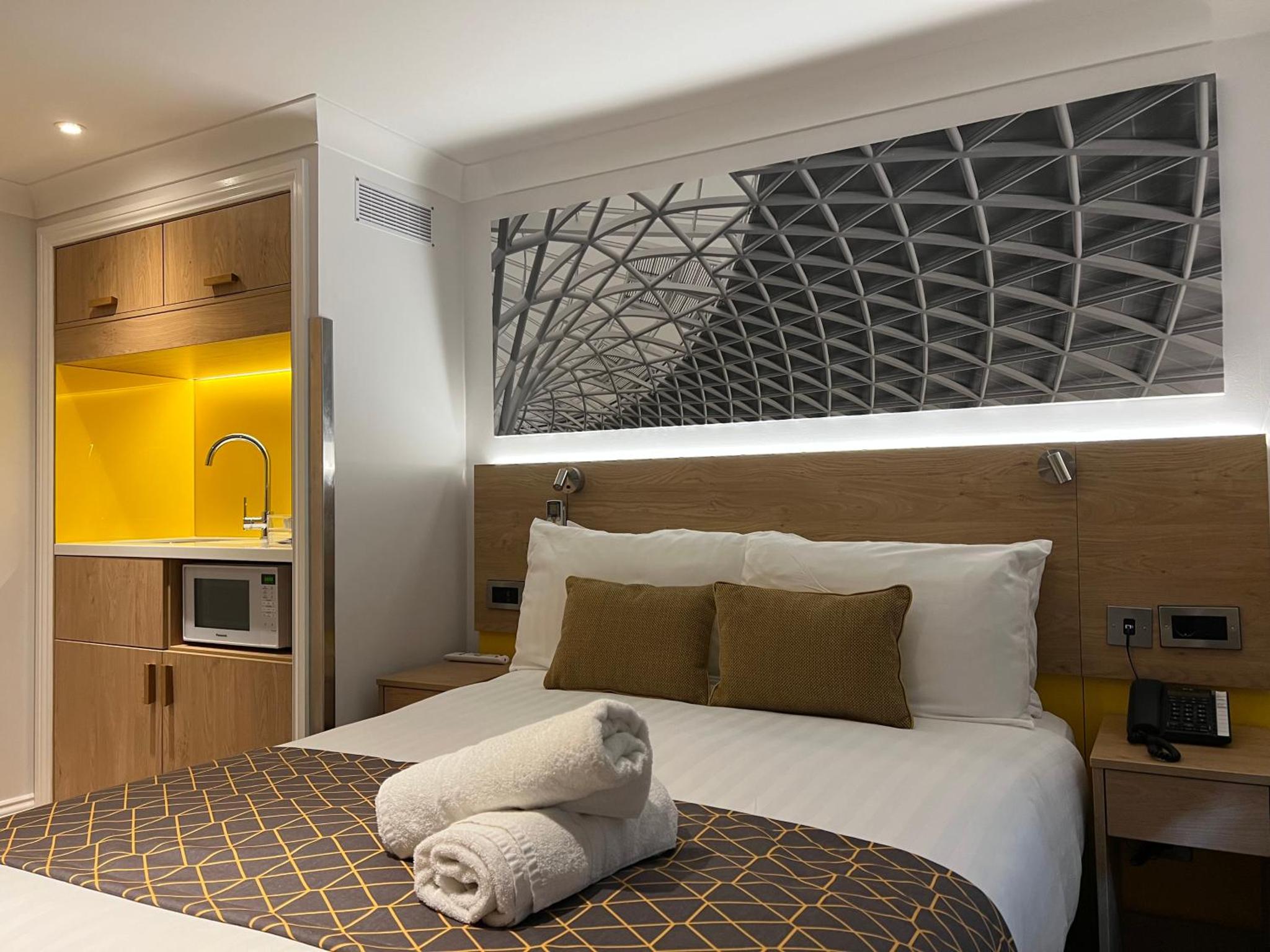 a hotel room with a bed with a towel on it at The Suites - St Pancras Hotel Group in London