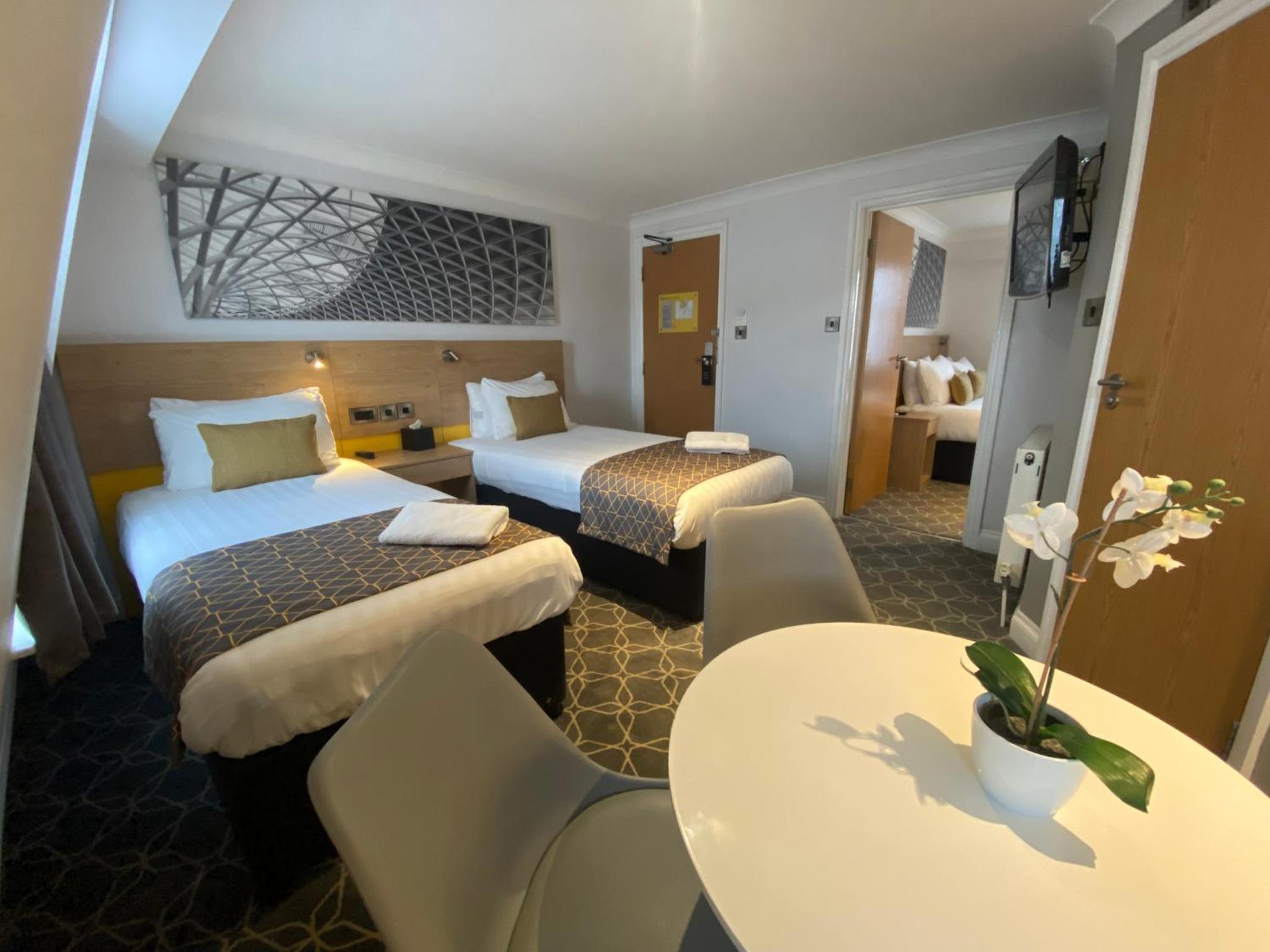 a hotel room with two beds and a table at The Suites - St Pancras Hotel Group in London +12 photos