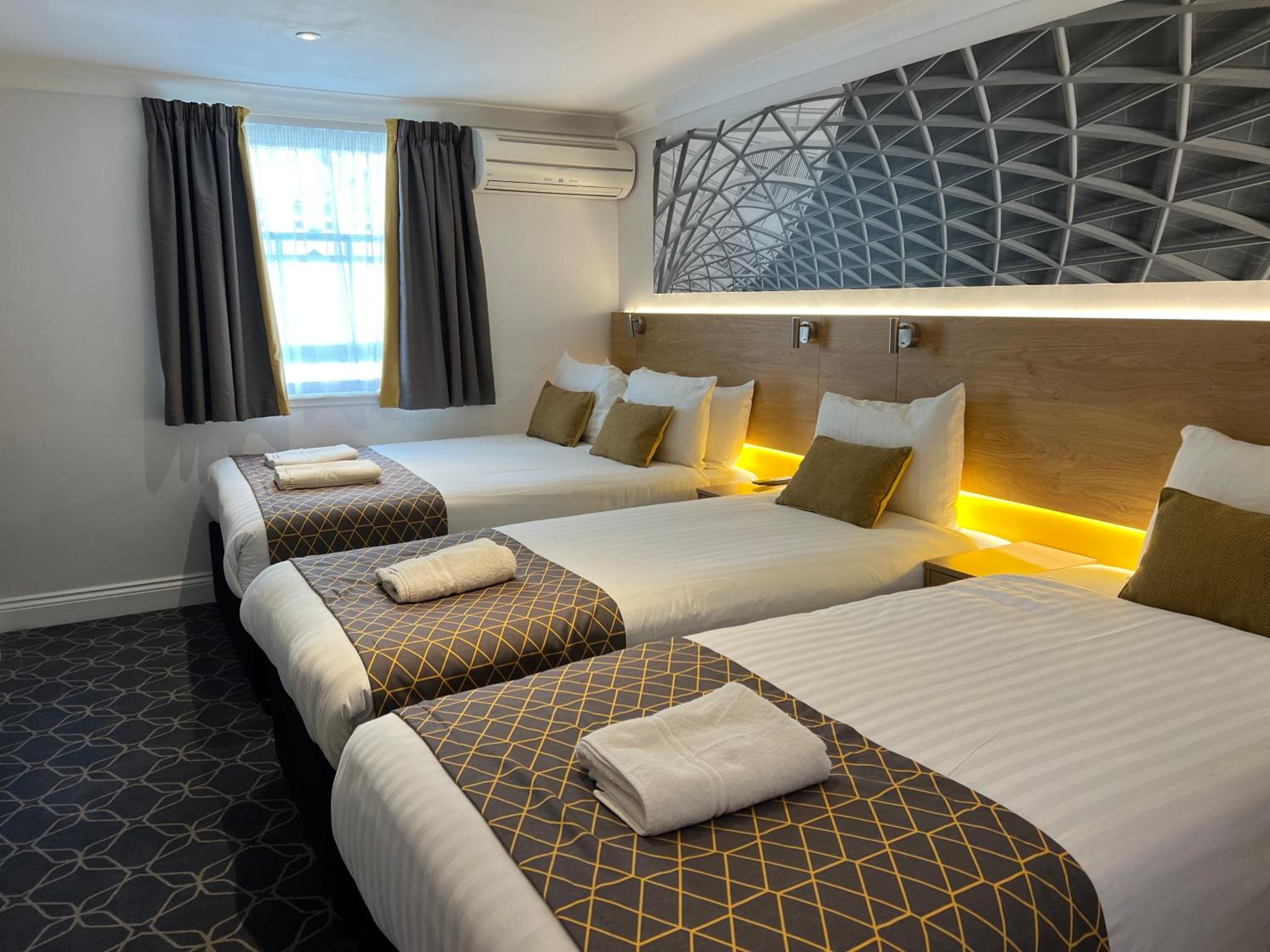 a hotel room with three beds in it at The Suites - St Pancras Hotel Group in London