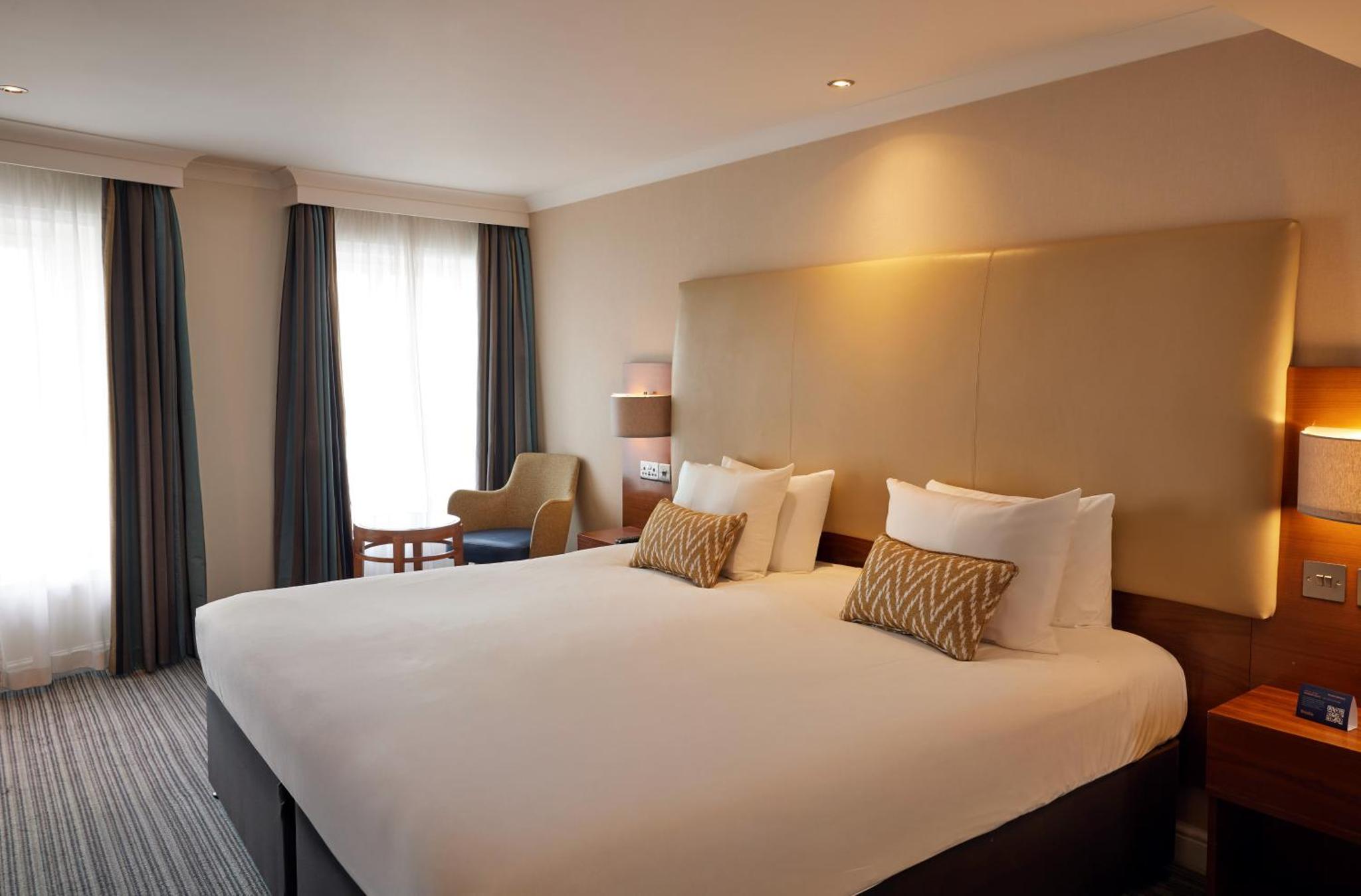 a hotel room with a large white bed with two pillows at Thistle London Piccadilly in London