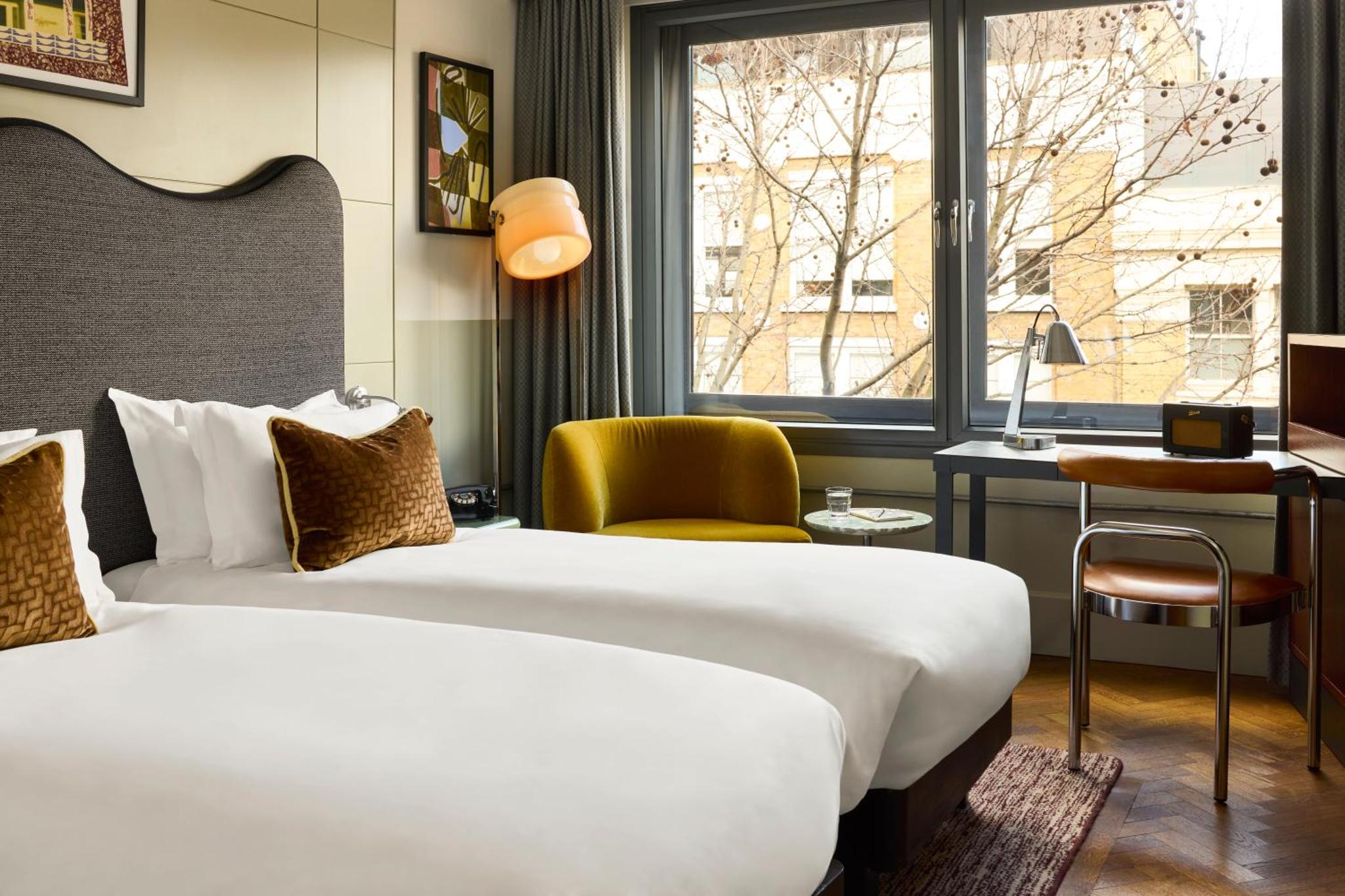 a hotel room with a bed and a desk and a window at The Hoxton, Shoreditch in London