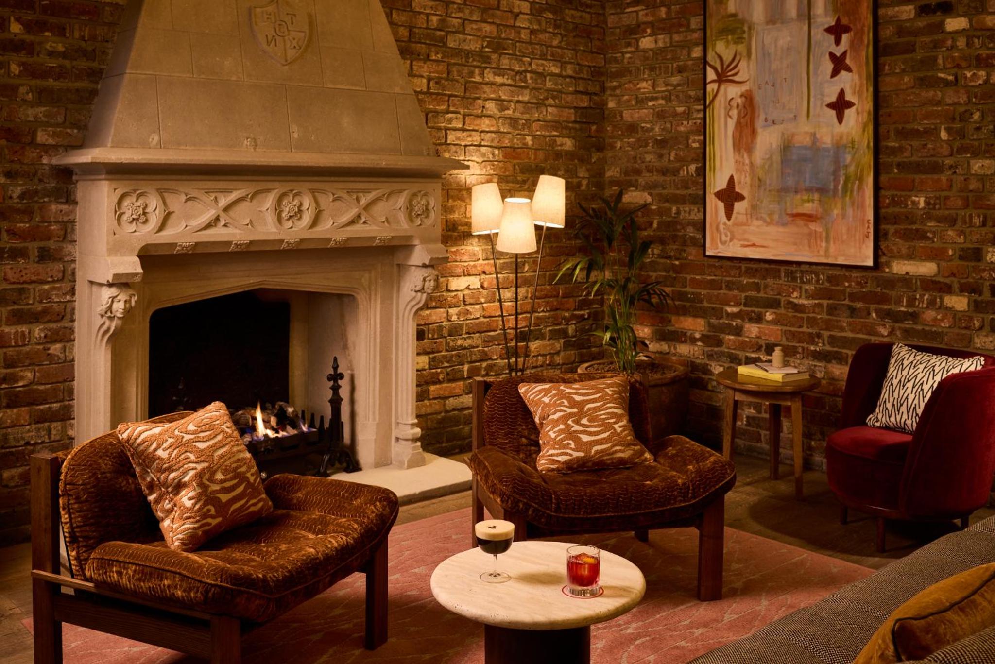 a living room with a fireplace and two chairs at The Hoxton, Shoreditch in London
