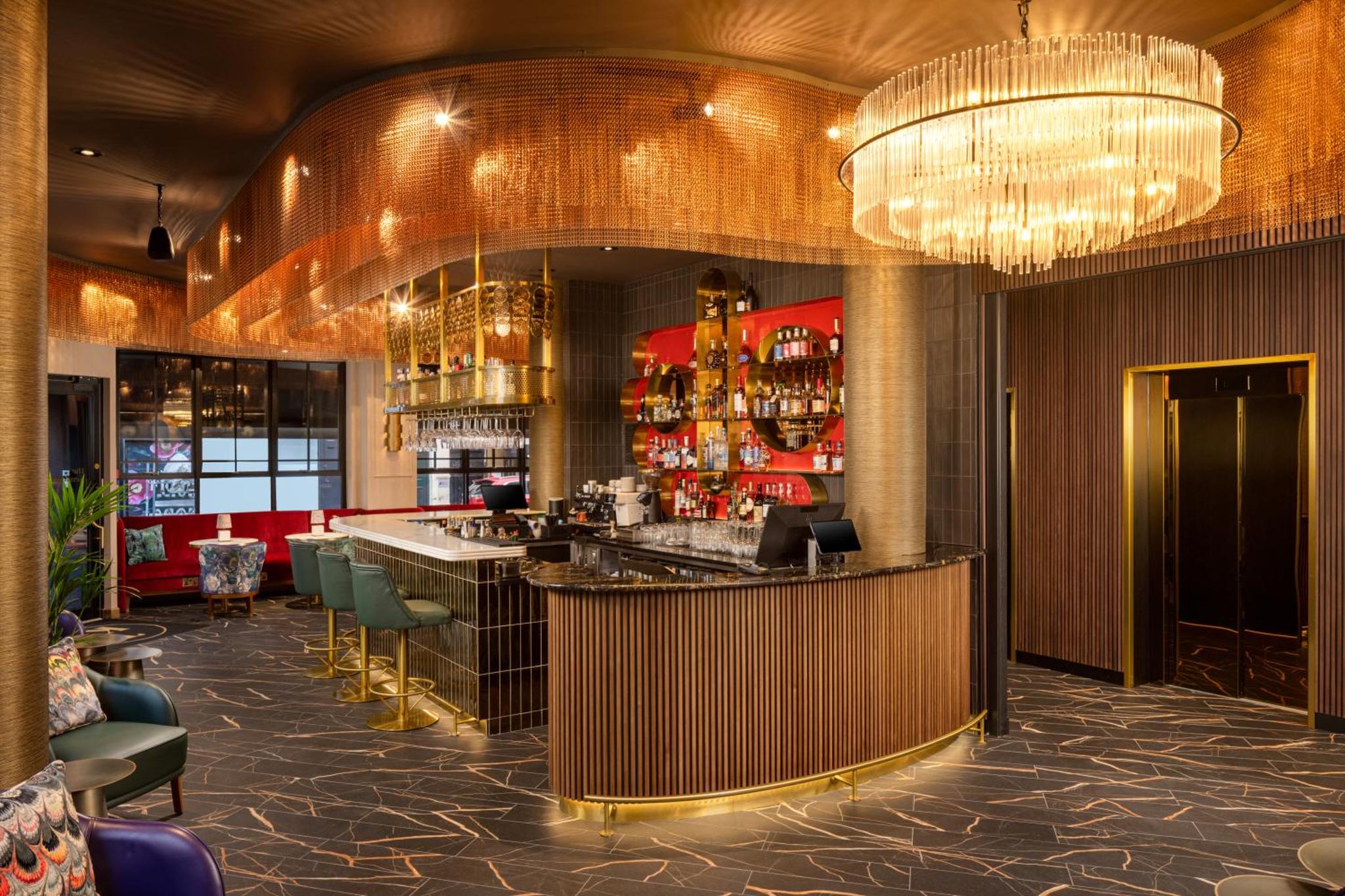 a bar in a restaurant with a chandelier at The Kensington Hideaway in London