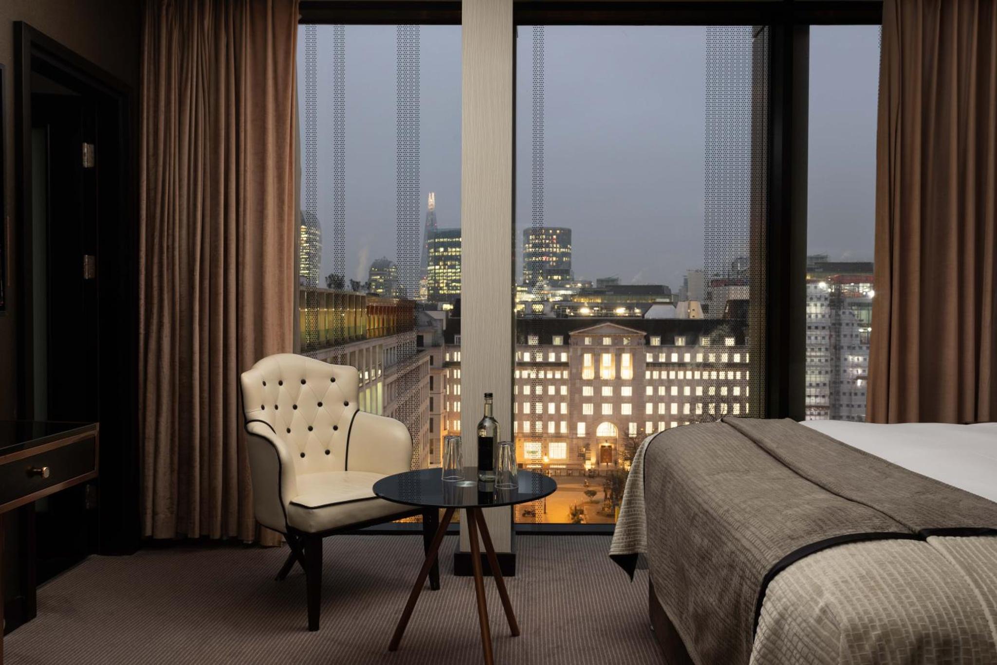 a hotel room with a bed and a table and a window at Montcalm Royal London House, London City in London