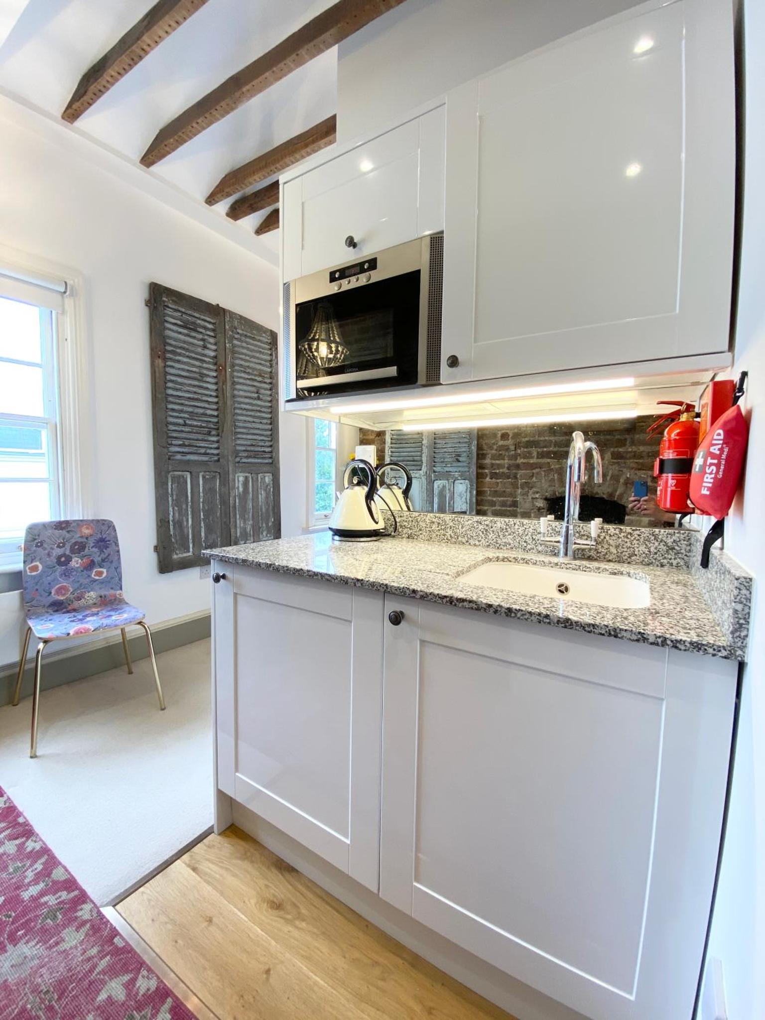 a kitchen with white cabinets and a sink at Stylish Studios in Pimlico & Victoria in London +15 photos