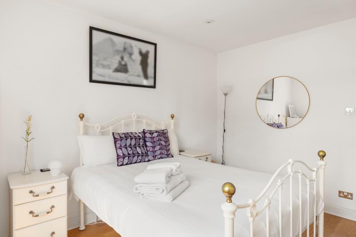 a bedroom with a white bed and a mirror at Spacious 1 Bed Maisonette in Camden by Amber Stays, Perfect for Long Term Stays, Sleeps 4 in London
