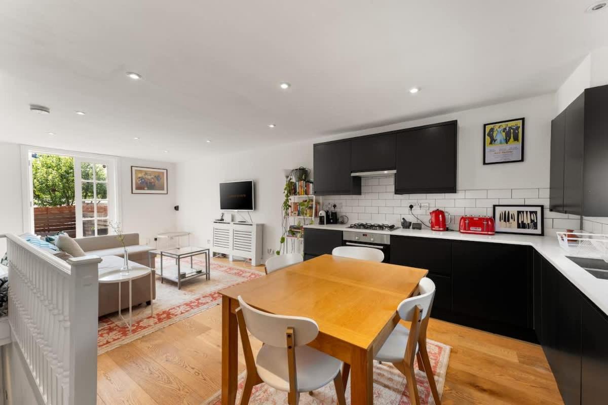 a kitchen and living room with a wooden table and chairs at Spacious 1 Bed Maisonette in Camden by Amber Stays, Perfect for Long Term Stays, Sleeps 4 in London