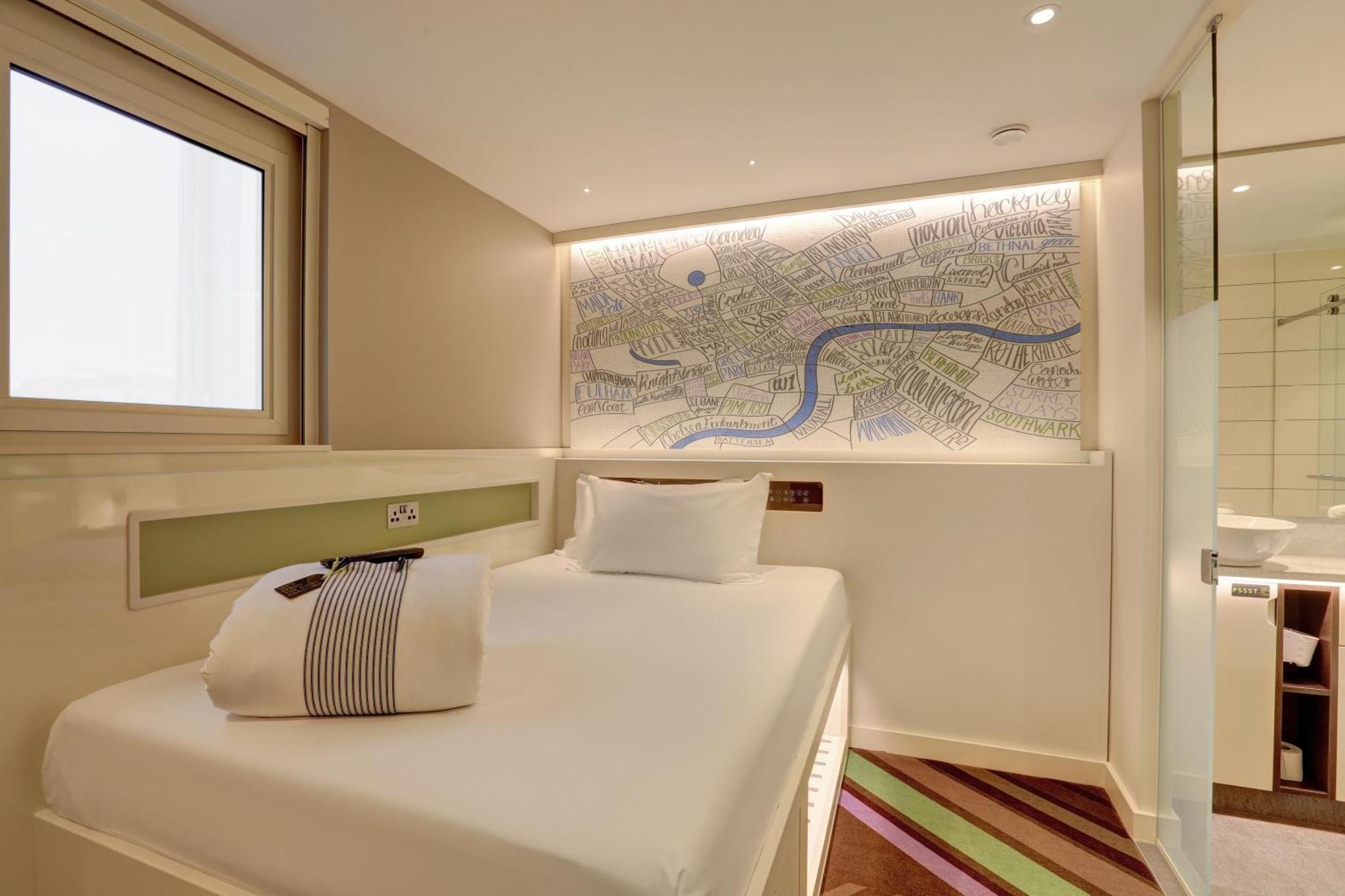 a bed in a room with a map on the wall at hub London - Goodge Street in London