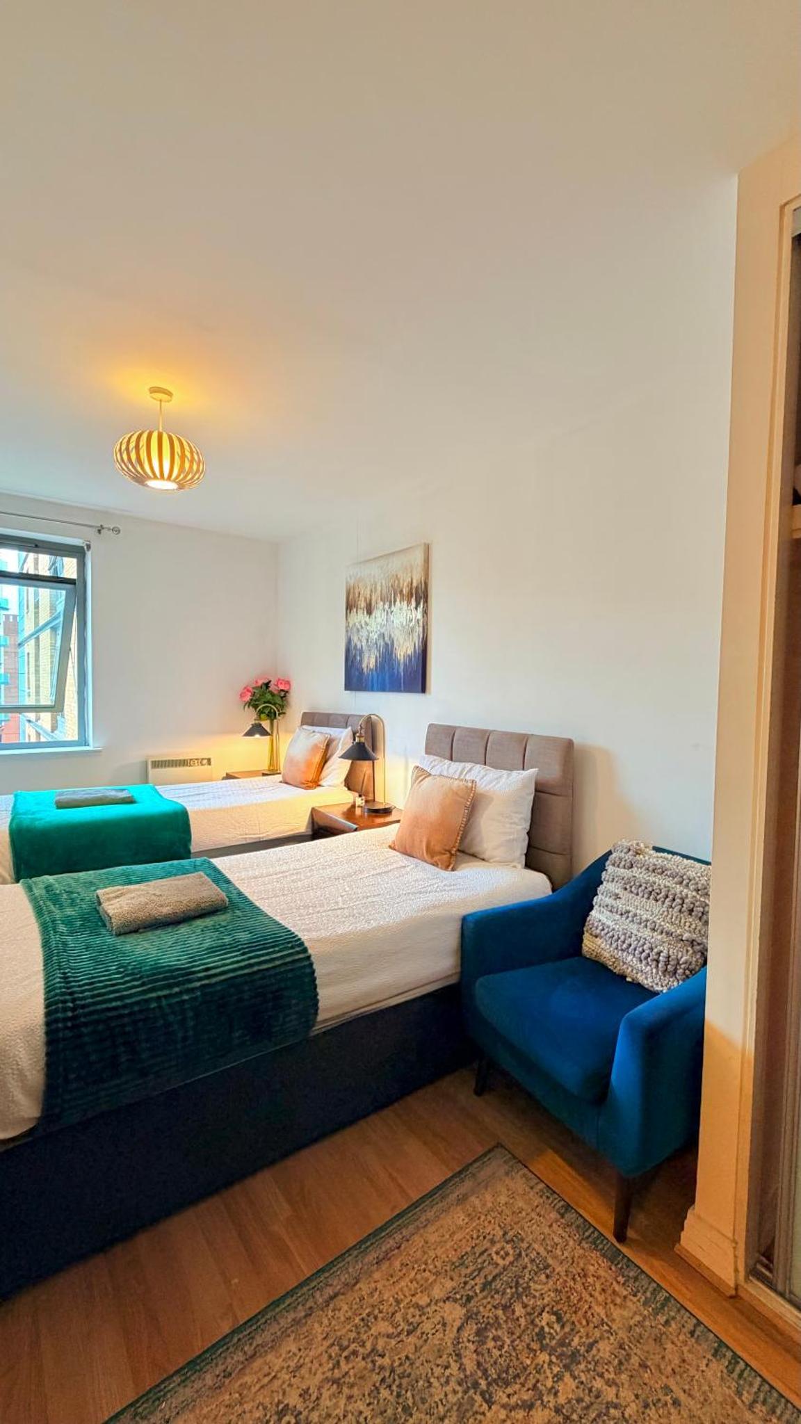 a bedroom with two beds and a blue chair at Two bed 2 bath opp tube station zone 2 in London