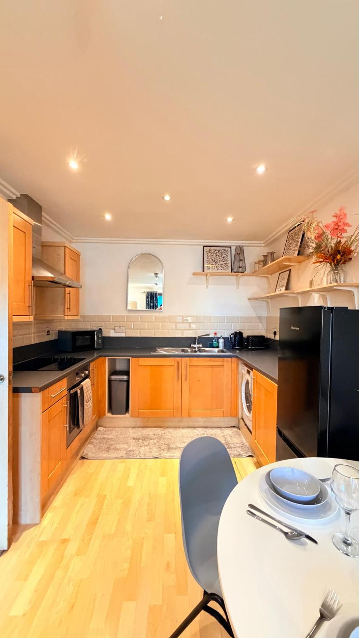 a kitchen with wooden cabinets and a table with chairs at Two bed 2 bath opp tube station zone 2 in London