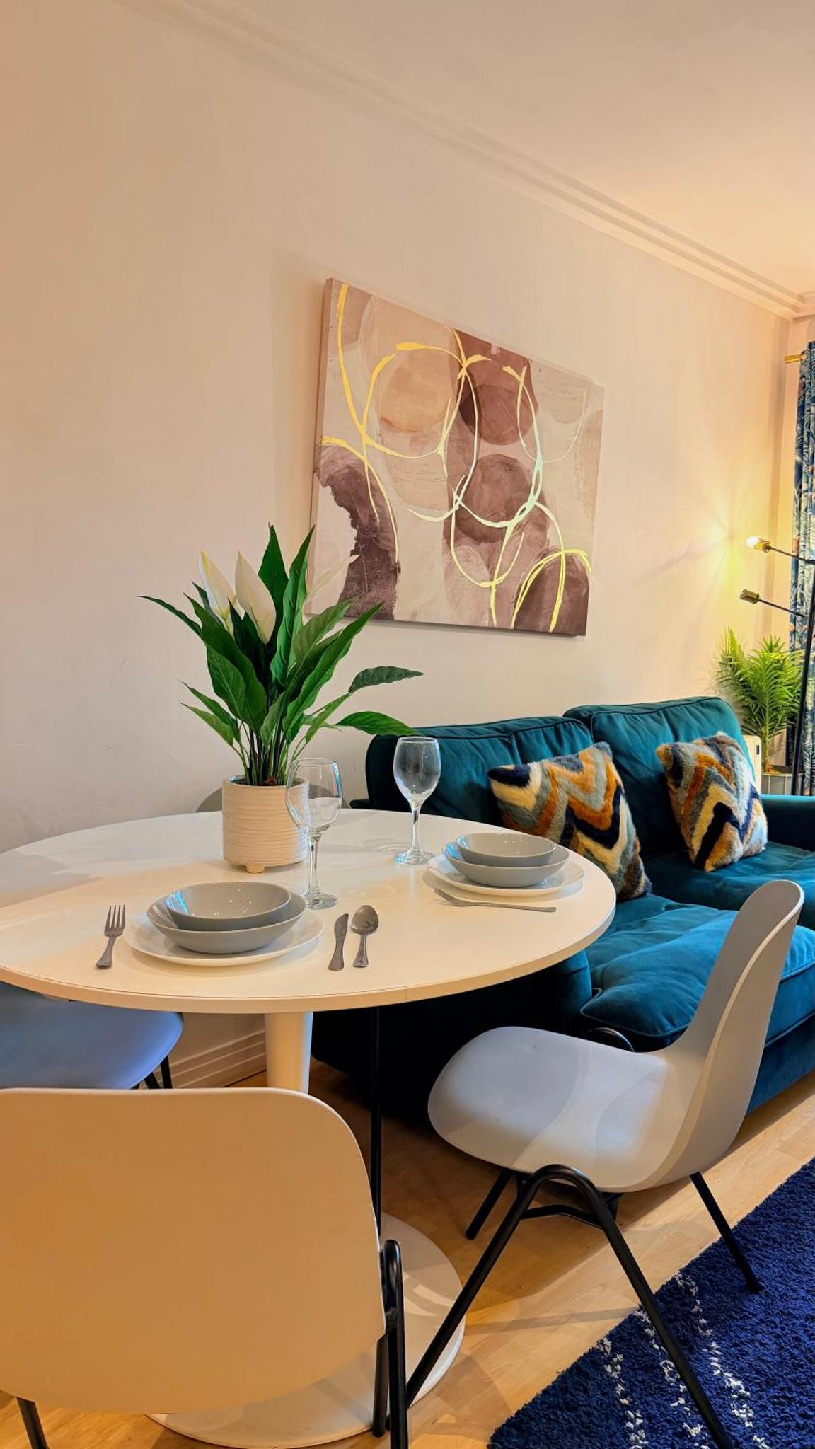 a living room with a table and a blue couch at Two bed 2 bath opp tube station zone 2 in London +8 photos