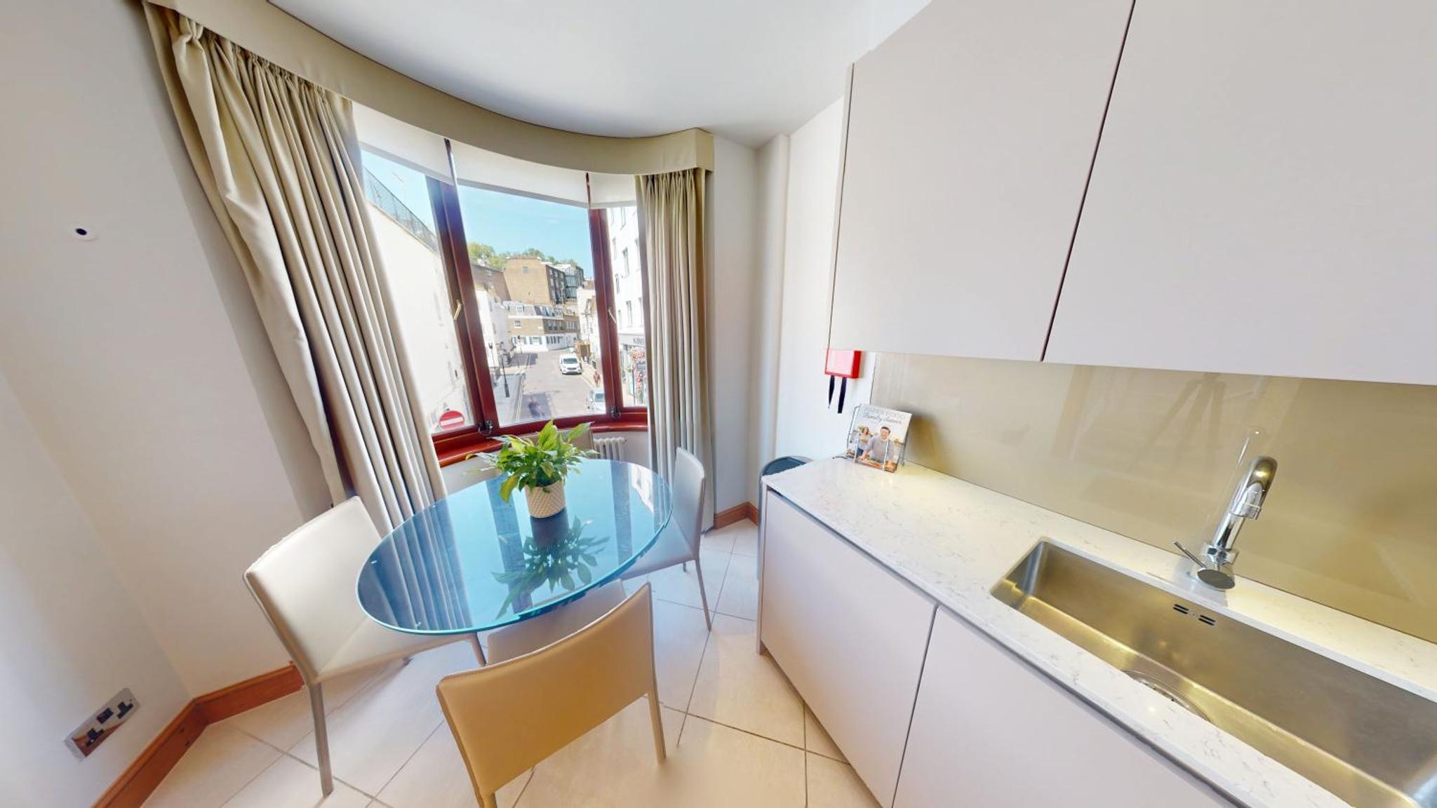 a kitchen with a glass table and a sink at Cheval Knightsbridge in London