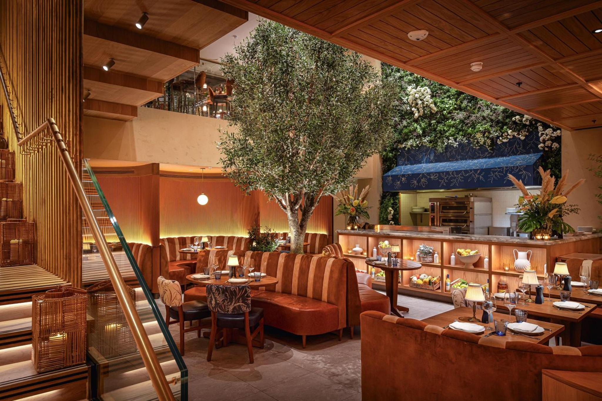 a restaurant with tables and chairs and a tree at The BoTree London, Curio Collection by Hilton in London