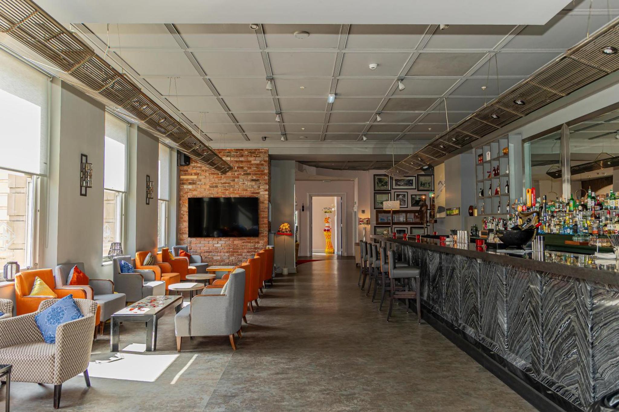 a restaurant with orange chairs and a bar at Hilton London Paddington in London