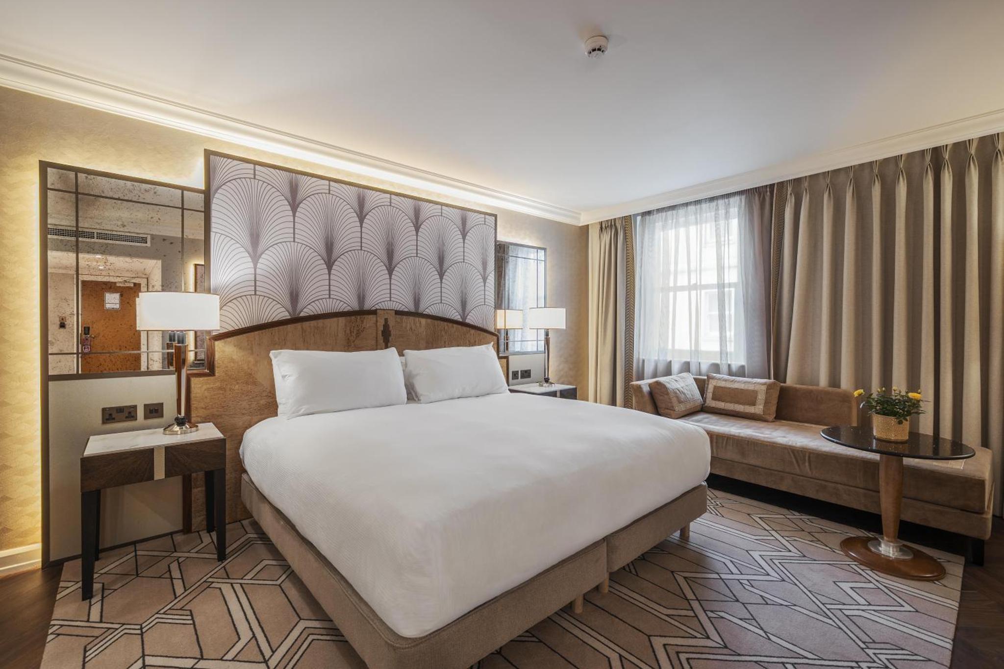 a hotel room with a large bed and a couch at Hilton London Paddington in London