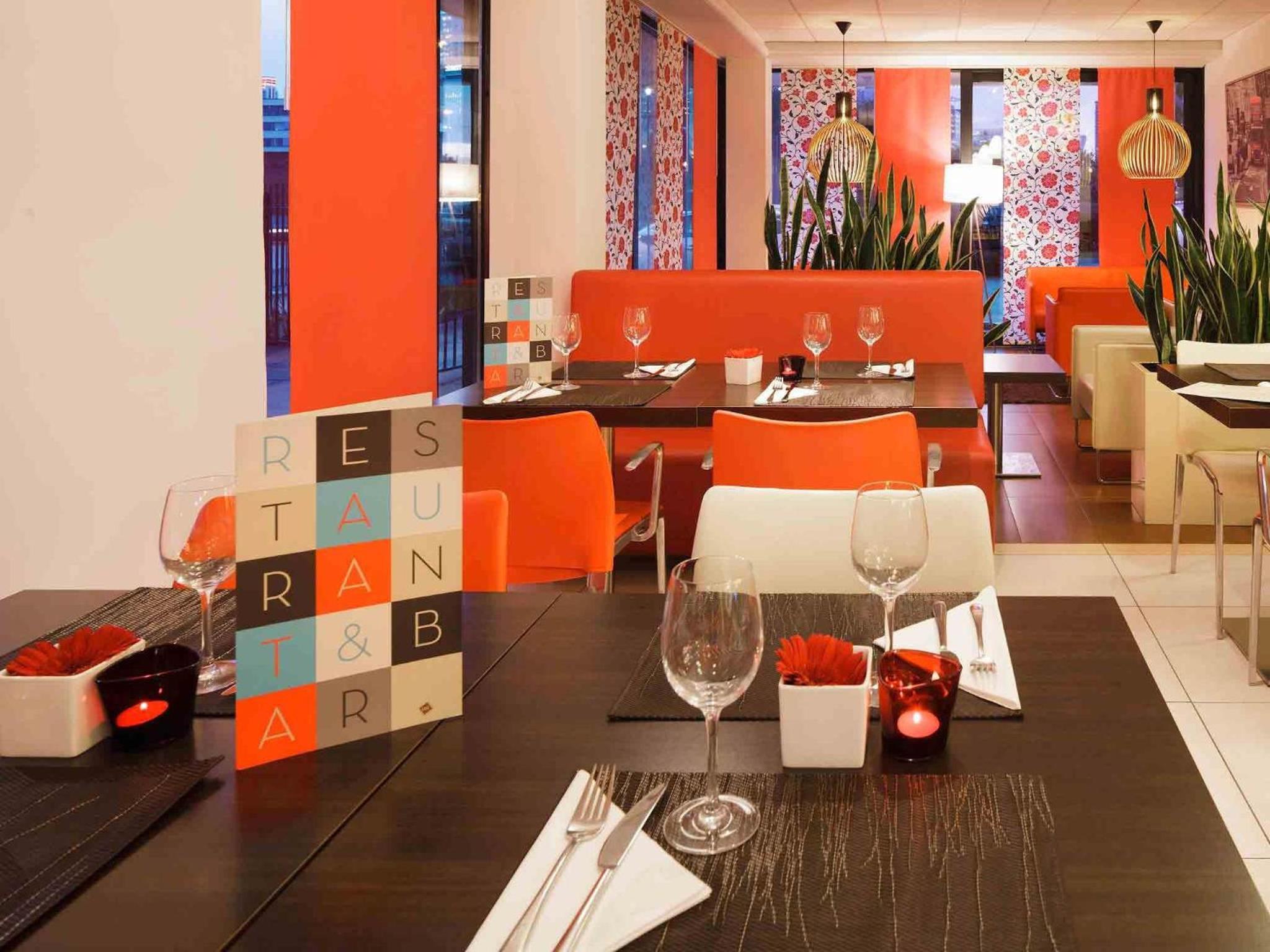 a dining room with a table and orange chairs at ibis London Docklands Canary Wharf in London +50 photos