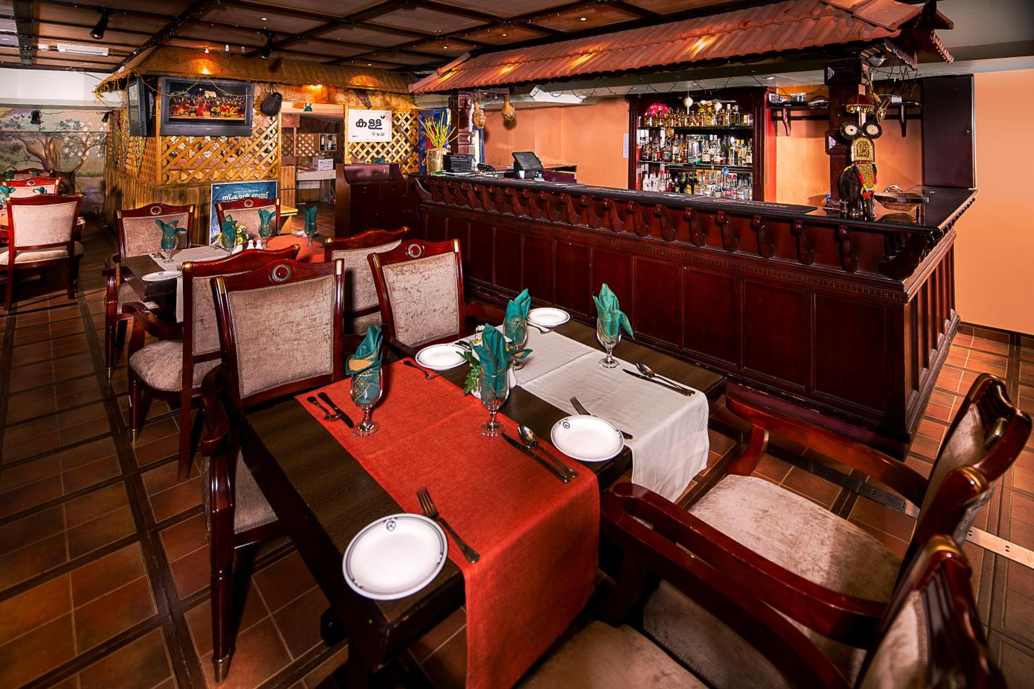 a restaurant with tables and chairs and a bar at Baisan International Hotel in Manama
