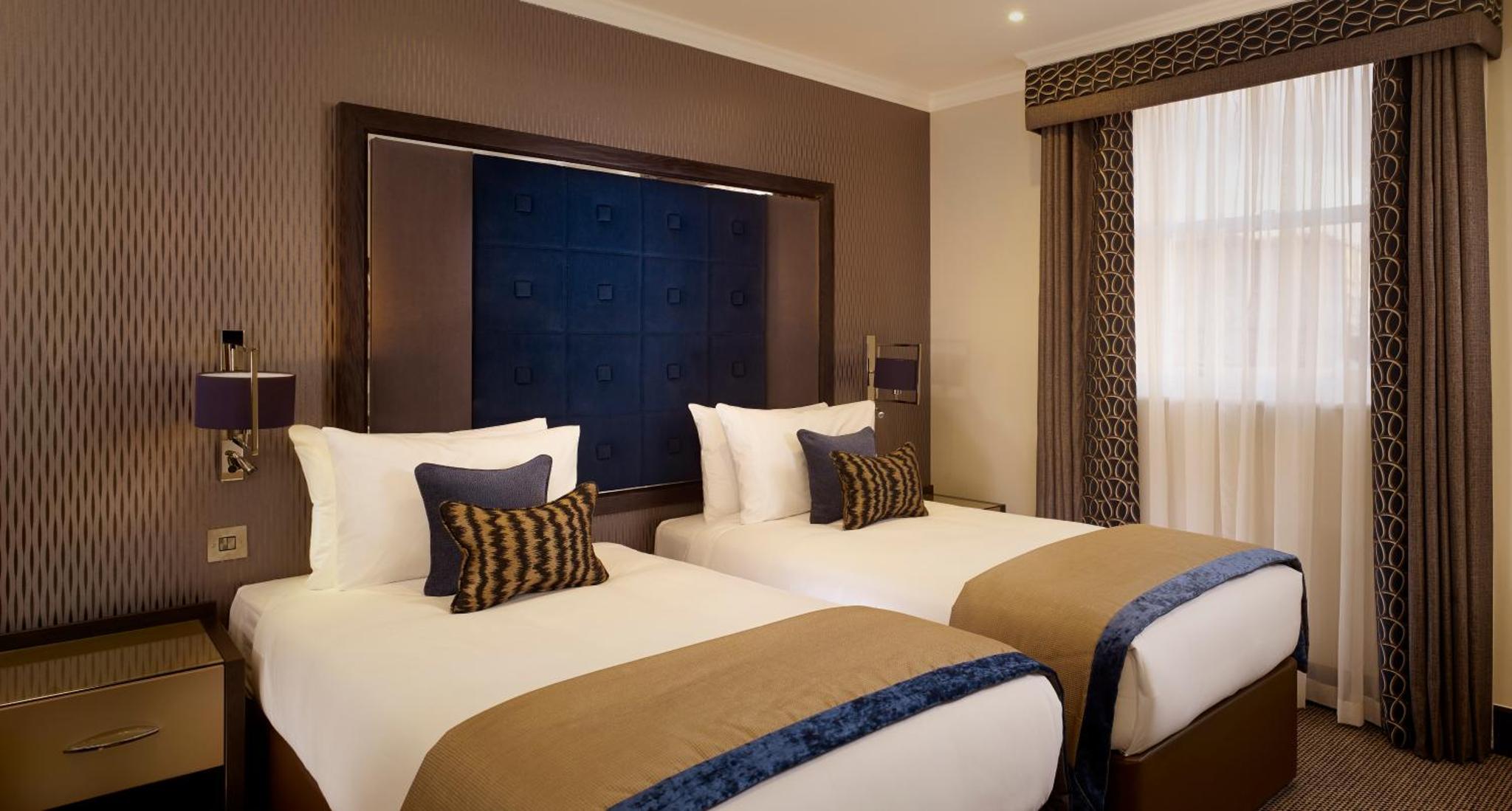 a hotel room with two beds and a window at The Westbourne Hyde Park in London