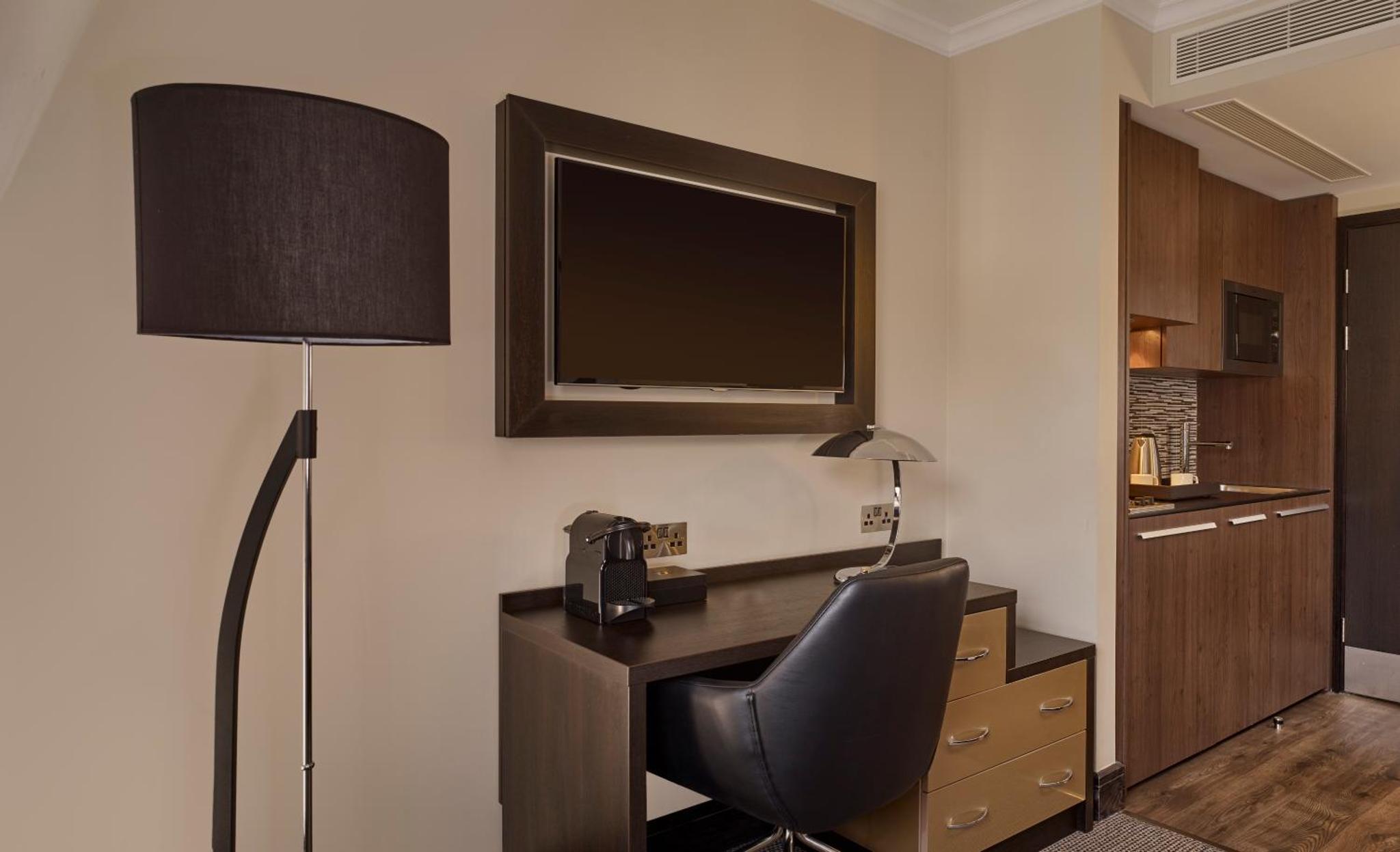 a room with a desk and a chair and a television at The Westbourne Hyde Park in London +18 photos