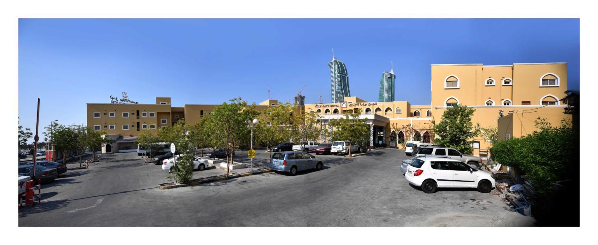 a parking lot with cars parked in front of a building at Gulf Gate Hotel in Manama