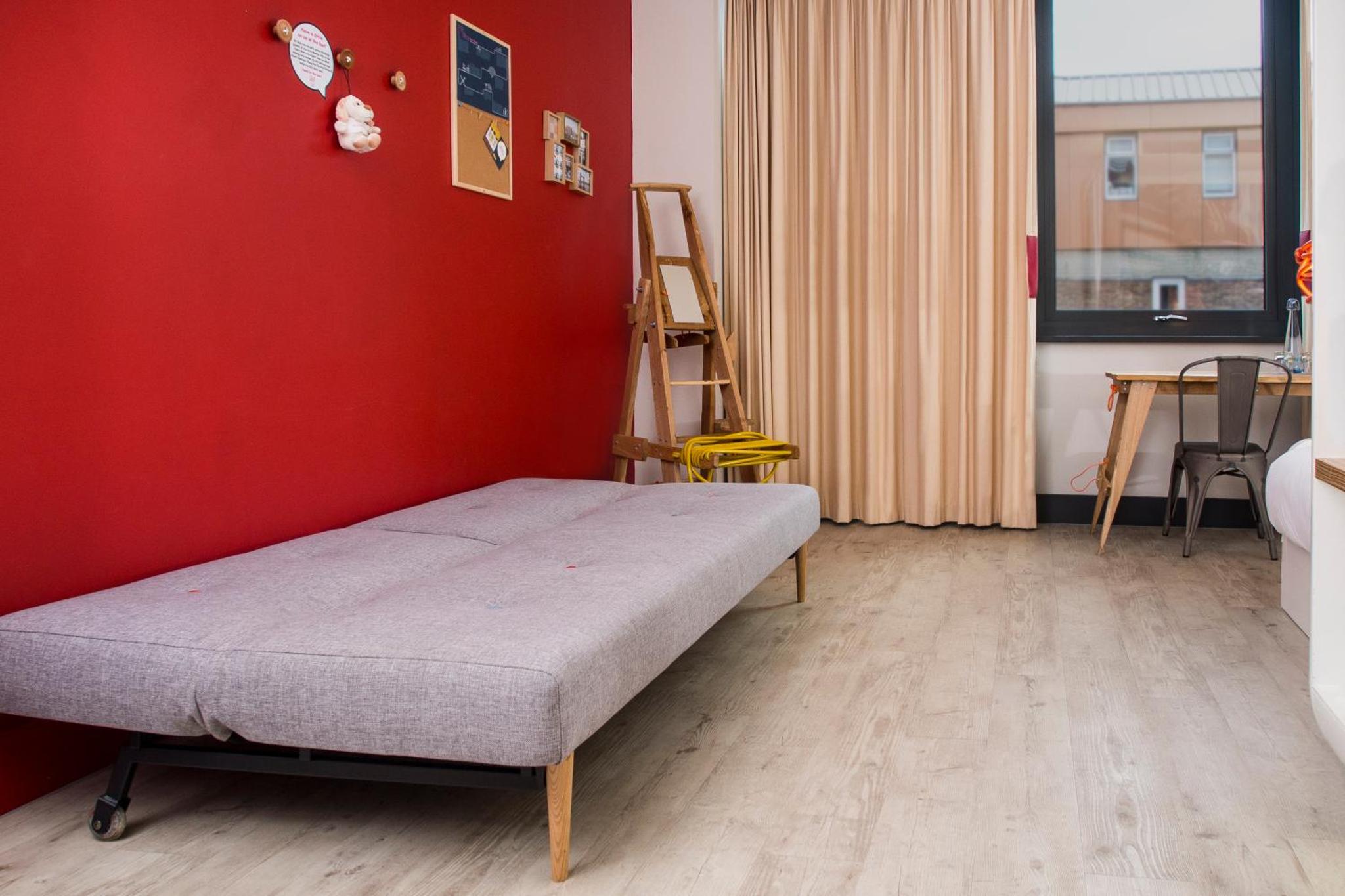 a bedroom with a bed and a red wall at The Corner London City in London +28 photos