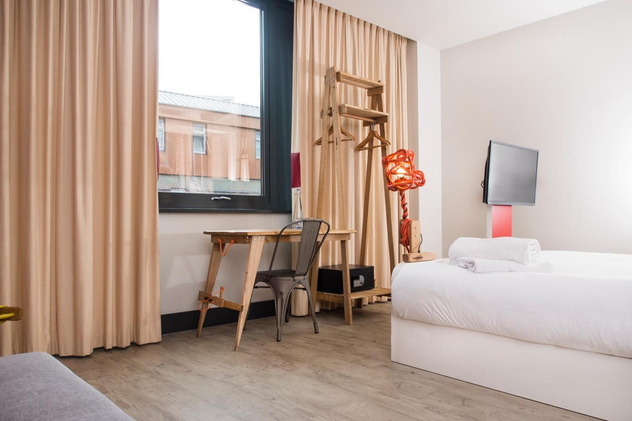 a bedroom with a bed and a desk and a window at The Corner London City in London