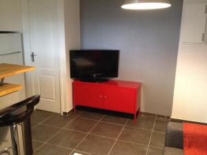 a red cabinet with a television on top of it at K&A Apartment in Aulnay-sous-Bois