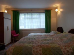 a bedroom with two beds and a window with green curtains at Arden Lodge in Oxford