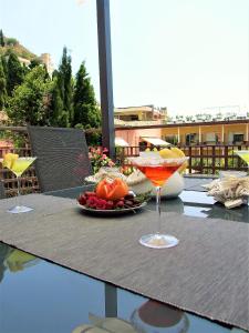 una mesa con una bebida y un plato de fruta en La Petite Maison, en Taormina